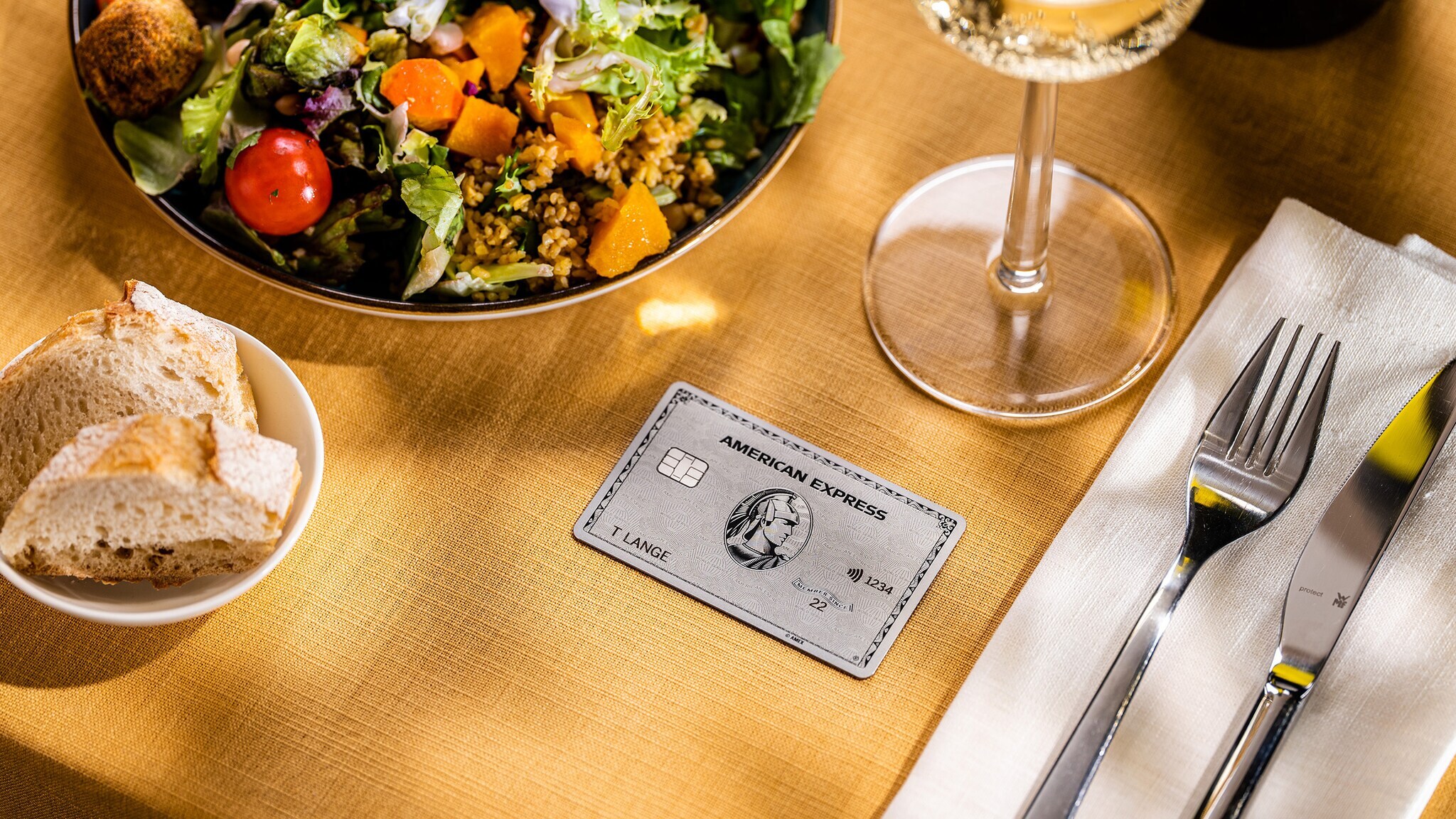 Eine Amex Platinum Card liegt auf einem gedeckten Tisch in einem gehobenen Restaurant