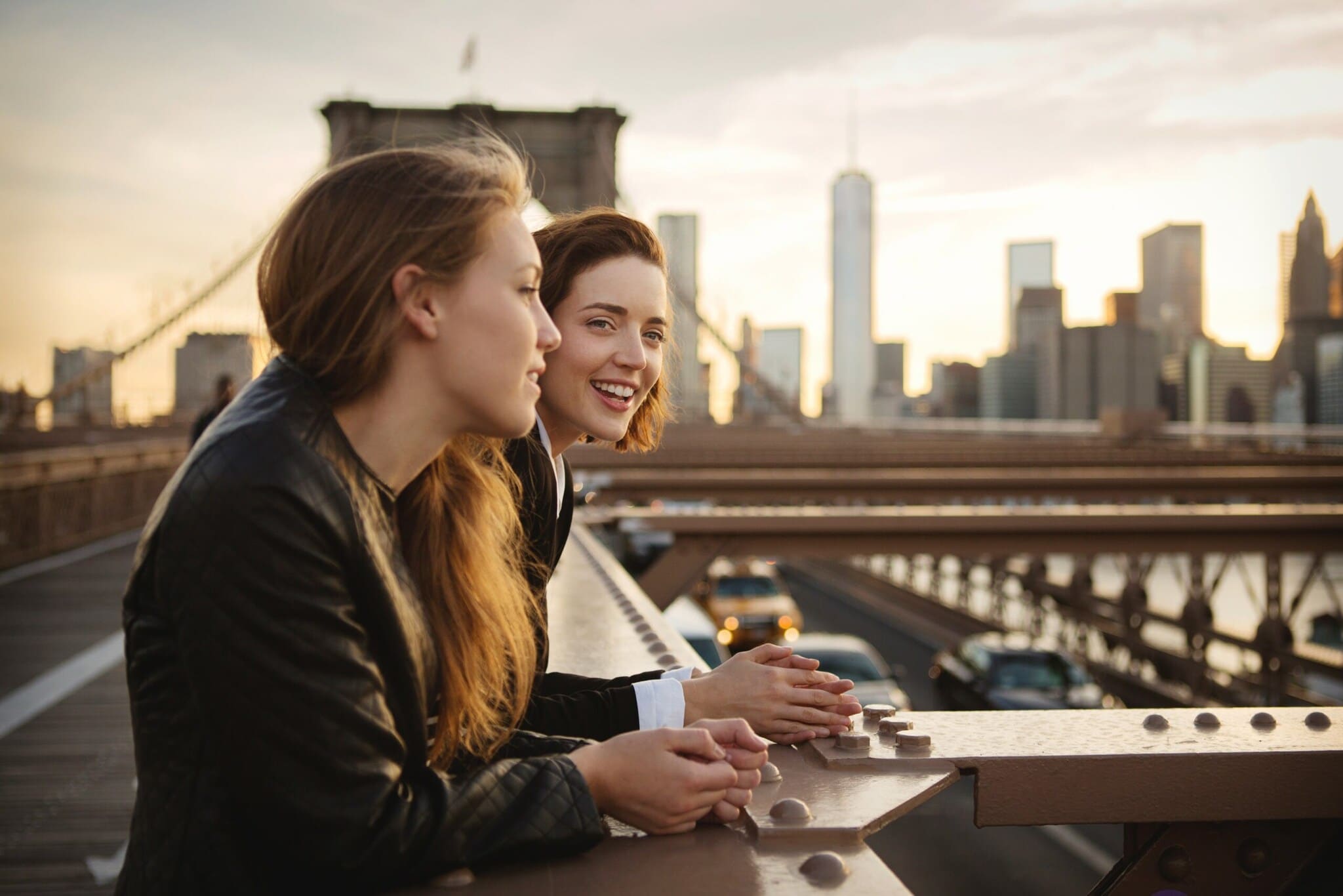 Zwei junge Mädchen stehen lächelnd auf der Brooklyn Bridge vor der Skyline Manhattans Zwei junge Mädchen stehen lächelnd auf der Brooklyn Bridge vor der Skyline Manhattans