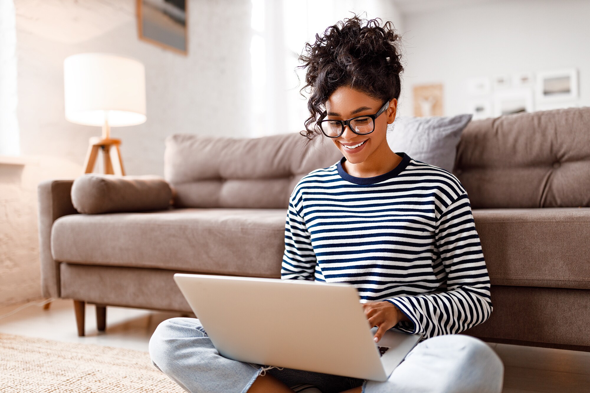 Membership Rewards Punkte: Dafür kannst du sie einlösen Eine gut gelaunte Frau sitzt zuhause am Laptop.