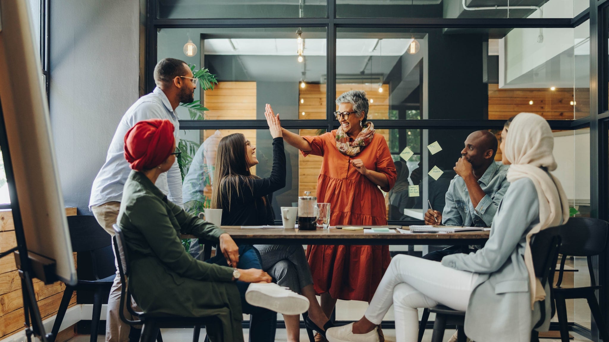 Sechs Personen multiethnischer Herkunft interagieren miteinander an einem Konferenztisch in einem Büro. Sechs Personen multiethnischer Herkunft interagieren miteinander an einem Konferenztisch in einem Büro.