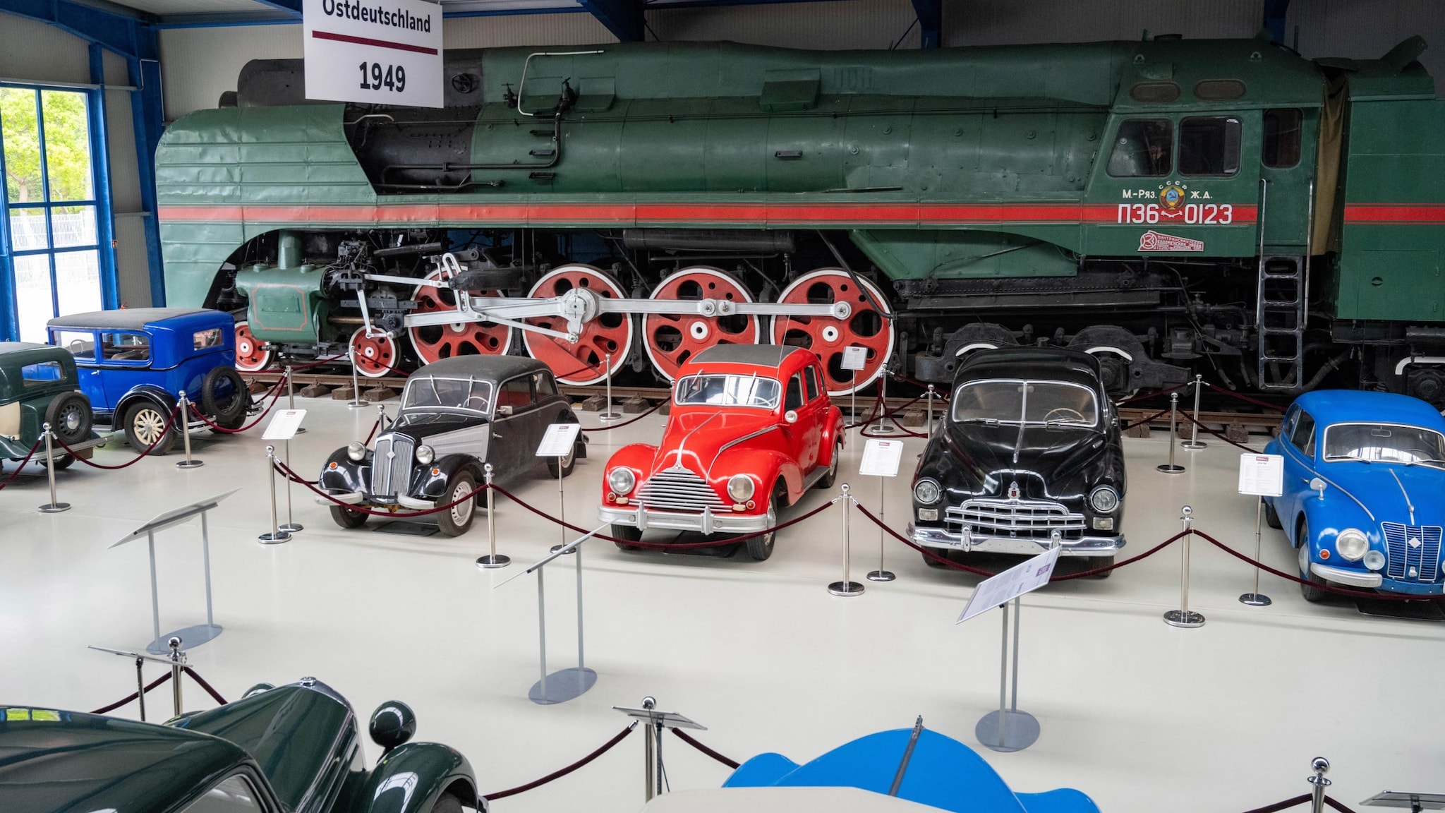 Aufgereihte Oldtimer-PKWs vor einem Eisenbahnwaggon in einer Ausstellungshalle. Aufgereihte Oldtimer-PKWs vor einem Eisenbahnwaggon in einer Ausstellungshalle.