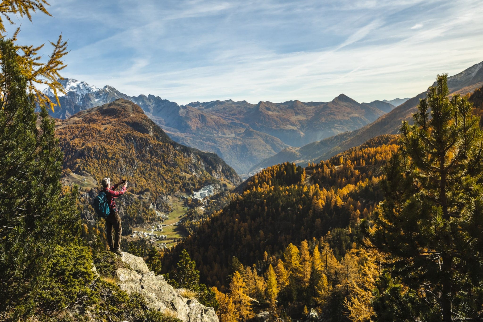 Wandernde Person, die mit einer Kamera in der Hand in einer bewaldeten Bergwelt steht. Wandernde Person, die mit einer Kamera in der Hand in einer bewaldeten Bergwelt steht.