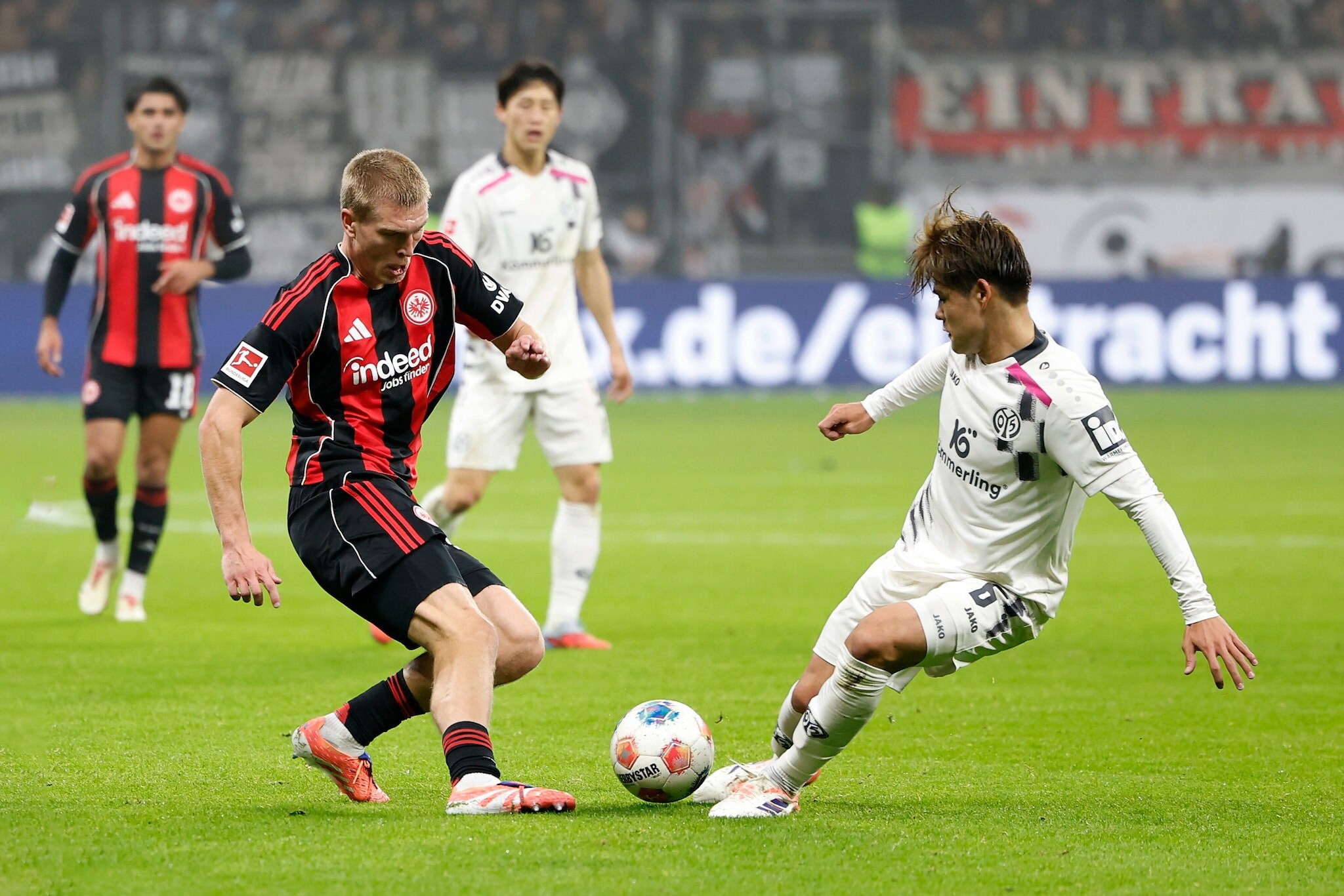Zwei Fußballspieler gegnerischer Mannschaften im Ballduell auf dem Rasen in einem Fußballstadion.