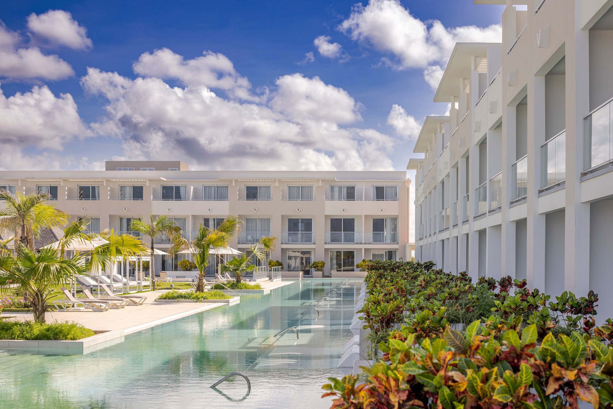 Moderne, dreistöckige Hotelanlage mit begrünter Poollandschaft.