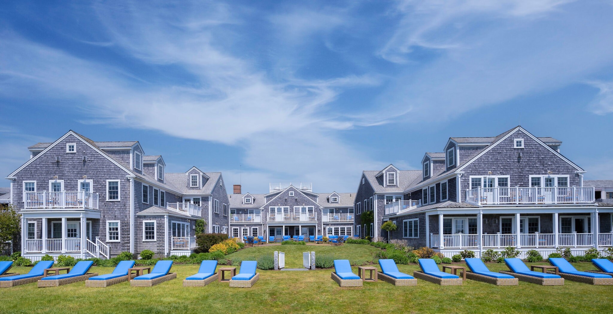 Blick auf die in U-Form stehenden Cottages des White Elephant, mit blau gepolsterten Liegen im Vordergrund.