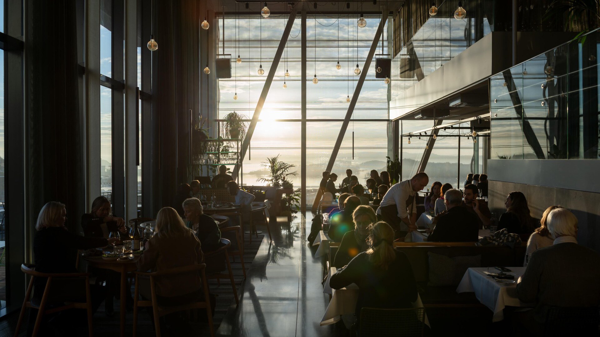 In einem Restaurant mit großen Glasfenstern stehen Tische und Stühle. In einem Restaurant mit großen Glasfenstern stehen Tische und Stühle.