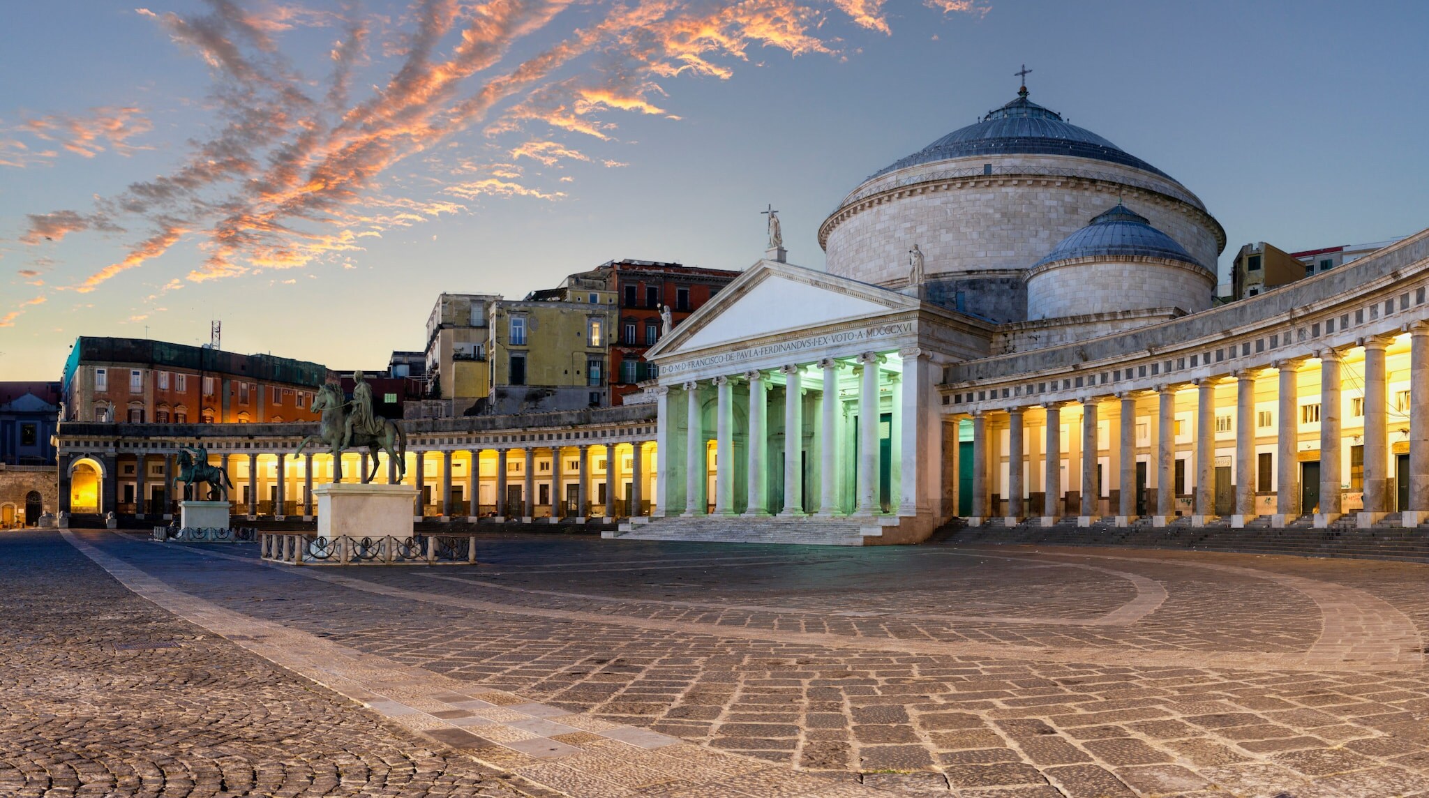 Die Piazza del Plebiscito in Neapel abends mit beleuchteten Kolonnaden.