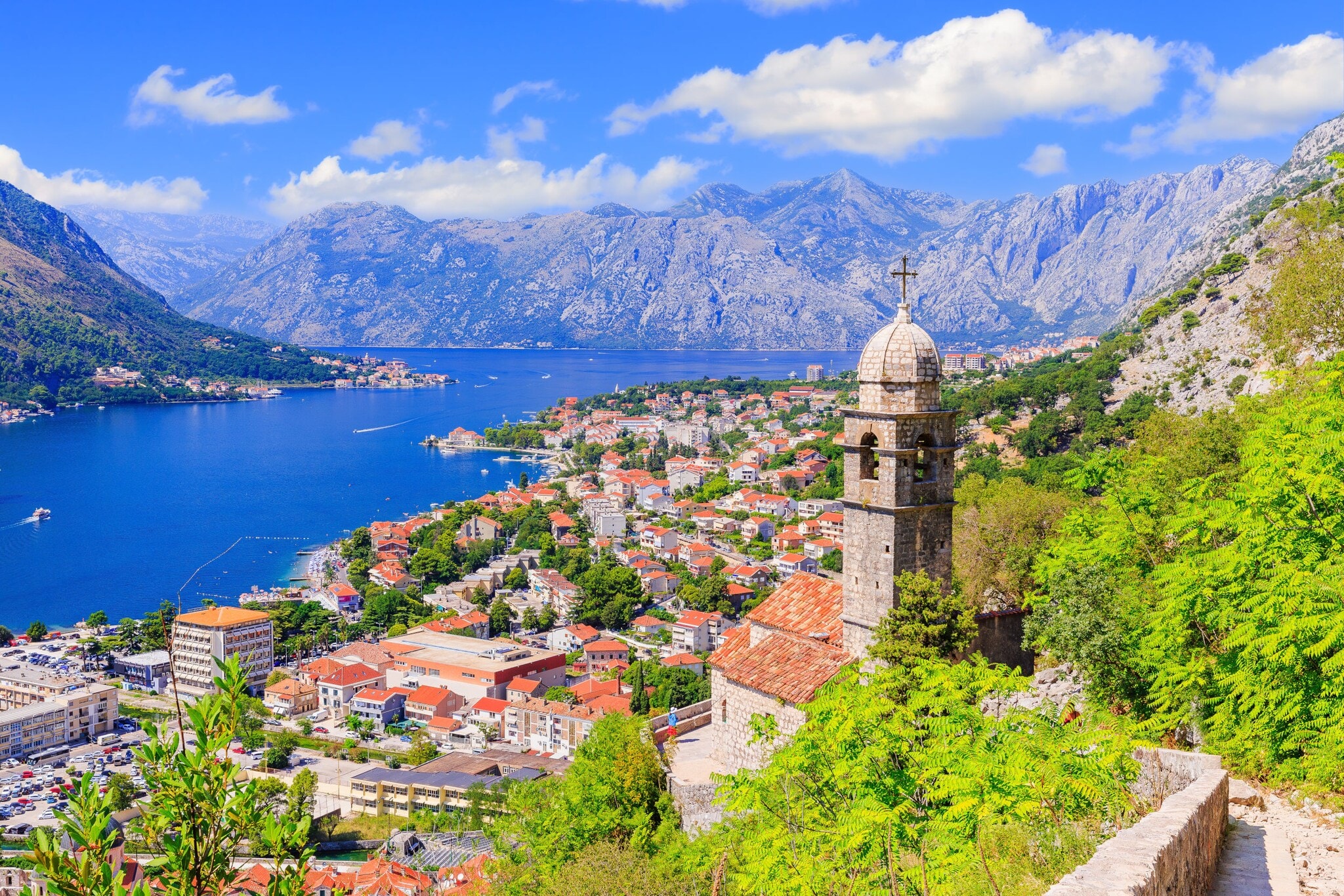 Blick auf die Stadt Kotor mit Häusern und Kirchturm, im Hintergrund Berge und eine Bucht. Blick auf die Stadt Kotor mit Häusern und Kirchturm, im Hintergrund Berge und eine Bucht.
