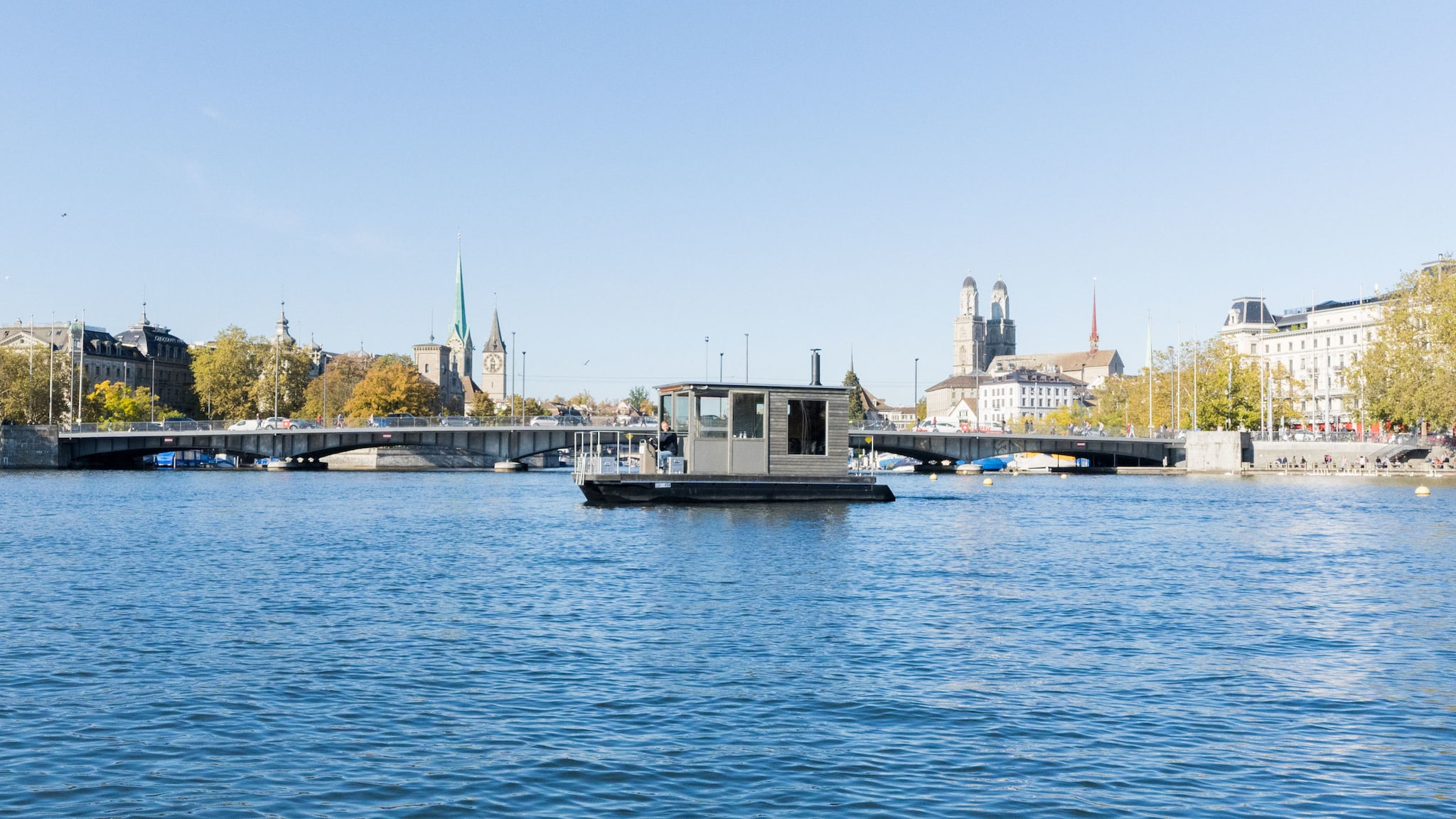 Eine Saunaboot auf einem See vor Stadtpanorama Zürichs.