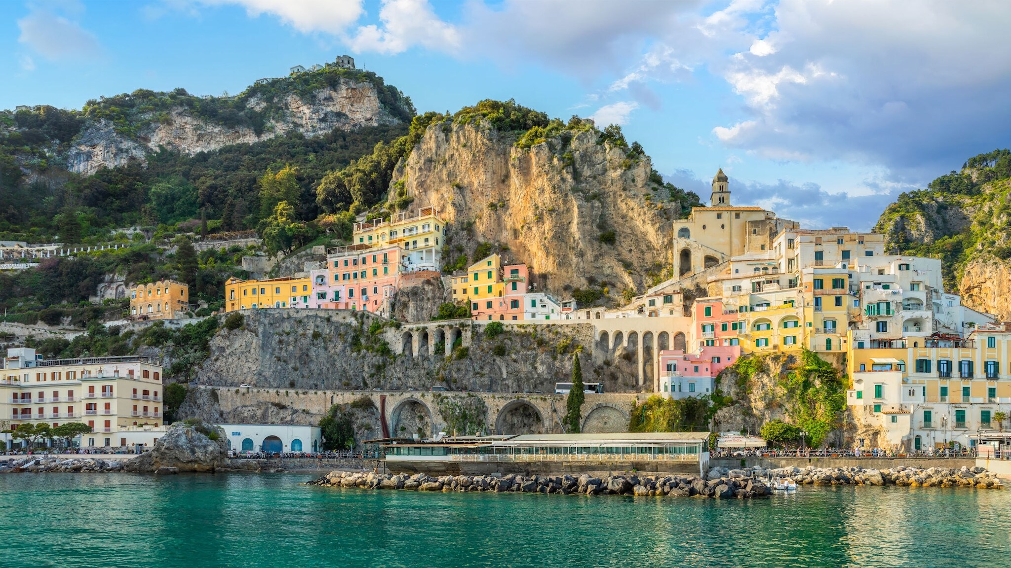 Ort mit bunten Häusern an der Amalfiküste, im Vordergrund türkisfarbenes Wasser. Ort mit bunten Häusern an der Amalfiküste, im Vordergrund türkisfarbenes Wasser.