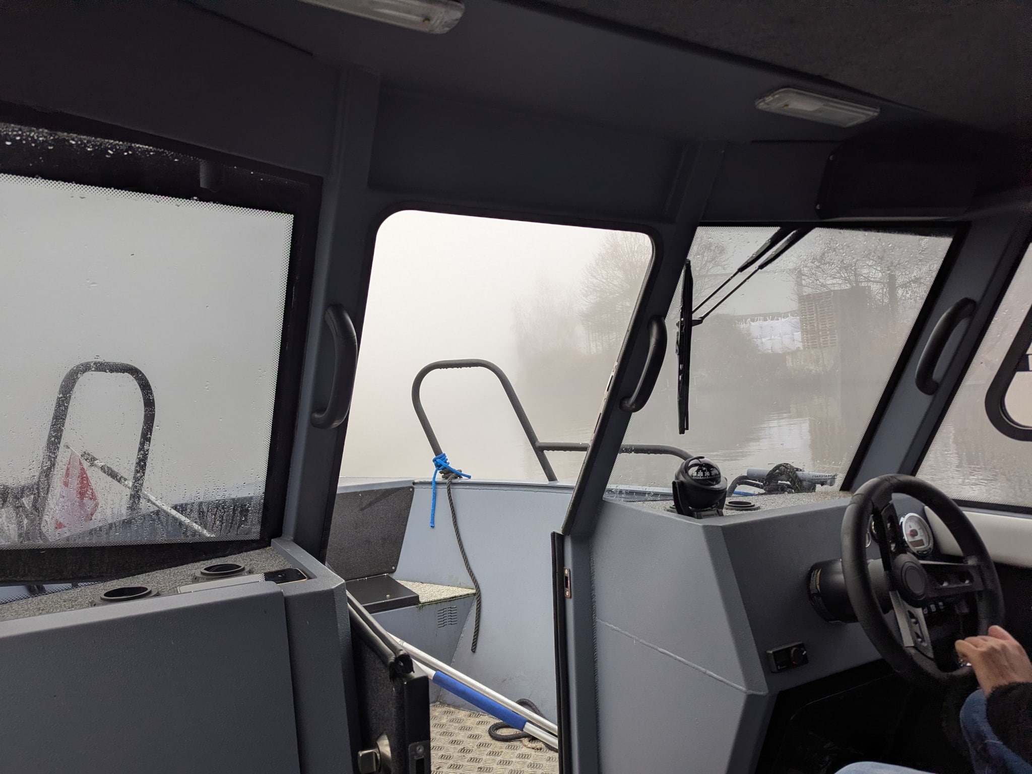 Blick aus dem Steuerhaus eines Motorboots auf eine Wasserstraße bei dichtem Nebel. Blick aus dem Steuerhaus eines Motorboots auf eine Wasserstraße bei dichtem Nebel.