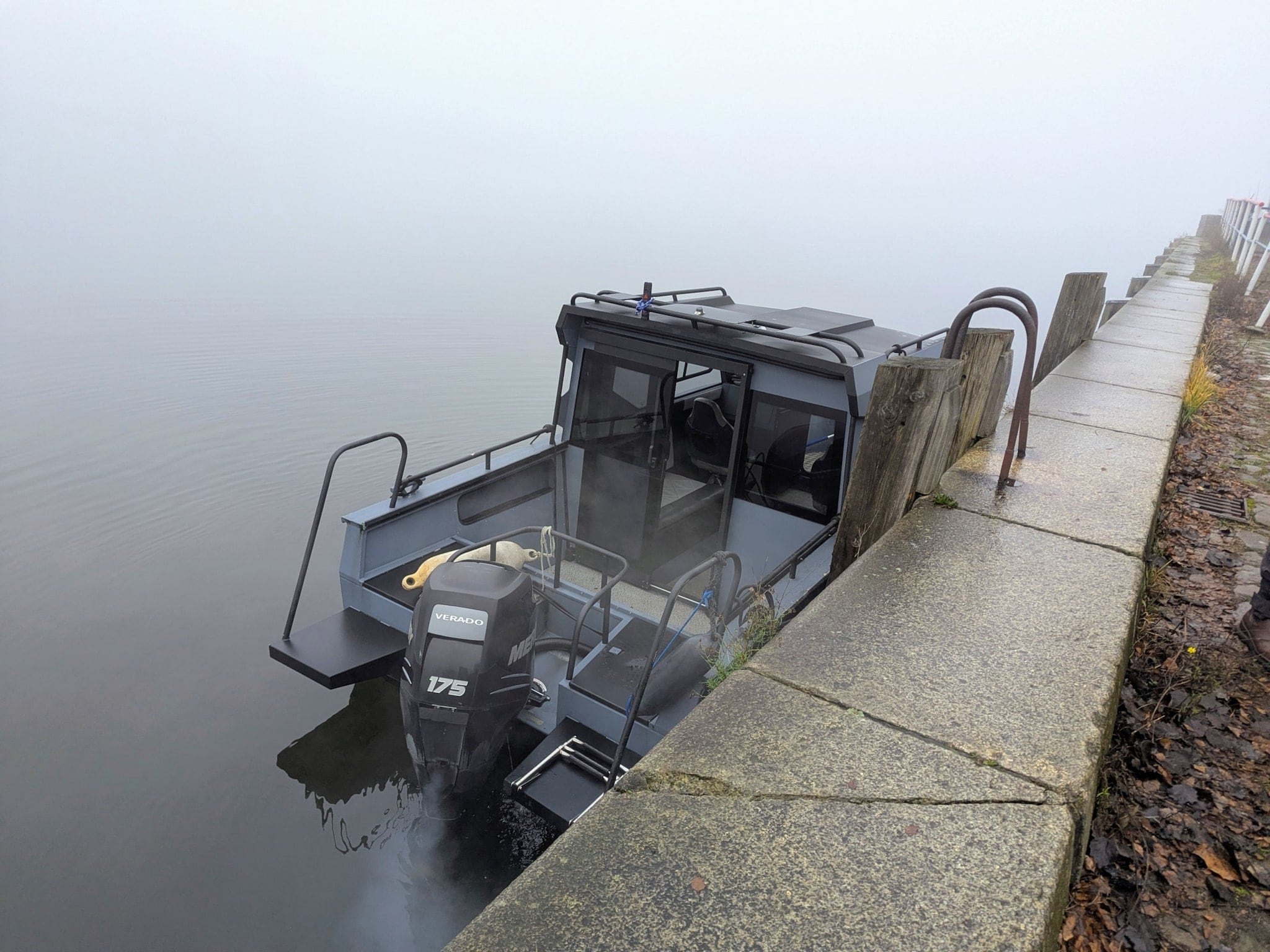 Ein Motorboot liegt bei dichtem Nebel an einer Kaimauer. Ein Motorboot liegt bei dichtem Nebel an einer Kaimauer.