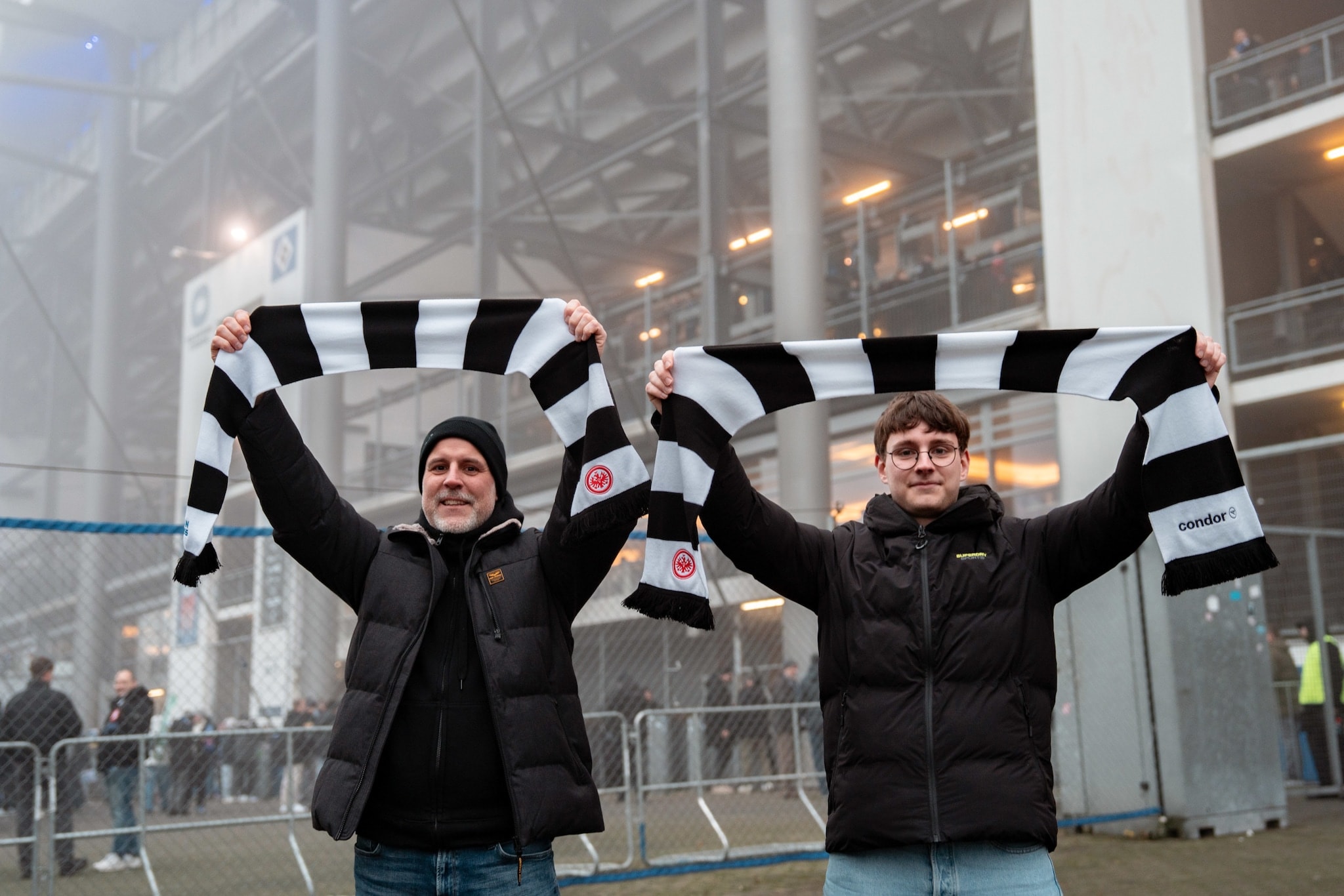 Zwei Gewinner vor dem Volksparkstadion halten Fanschals der Eintracht über ihren Köpfen hoch. Zwei Gewinner vor dem Volksparkstadion halten Fanschals der Eintracht über ihren Köpfen hoch.