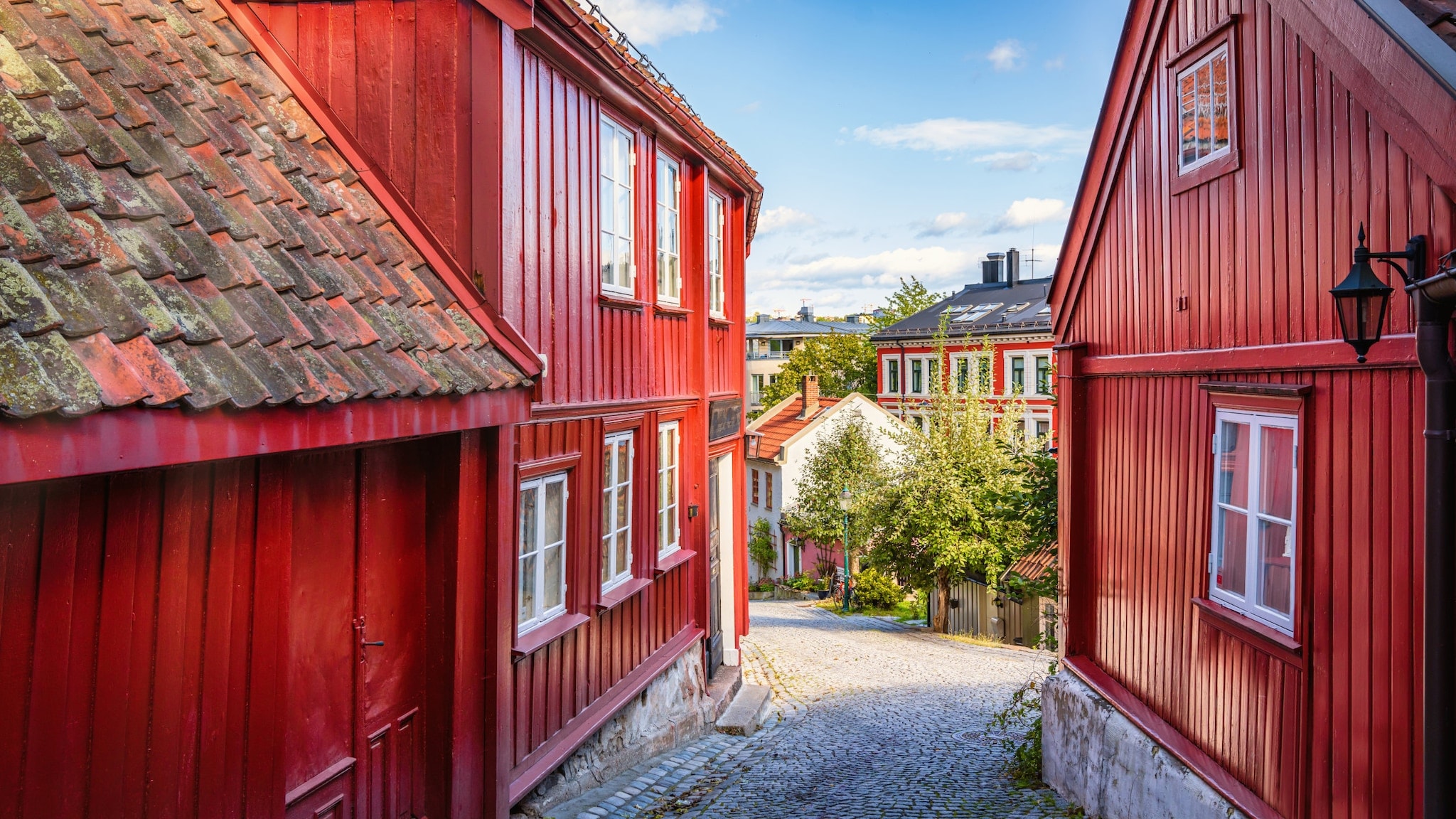 In einer kleinen Straße stehen rote Holzhäuser. In einer kleinen Straße stehen rote Holzhäuser.