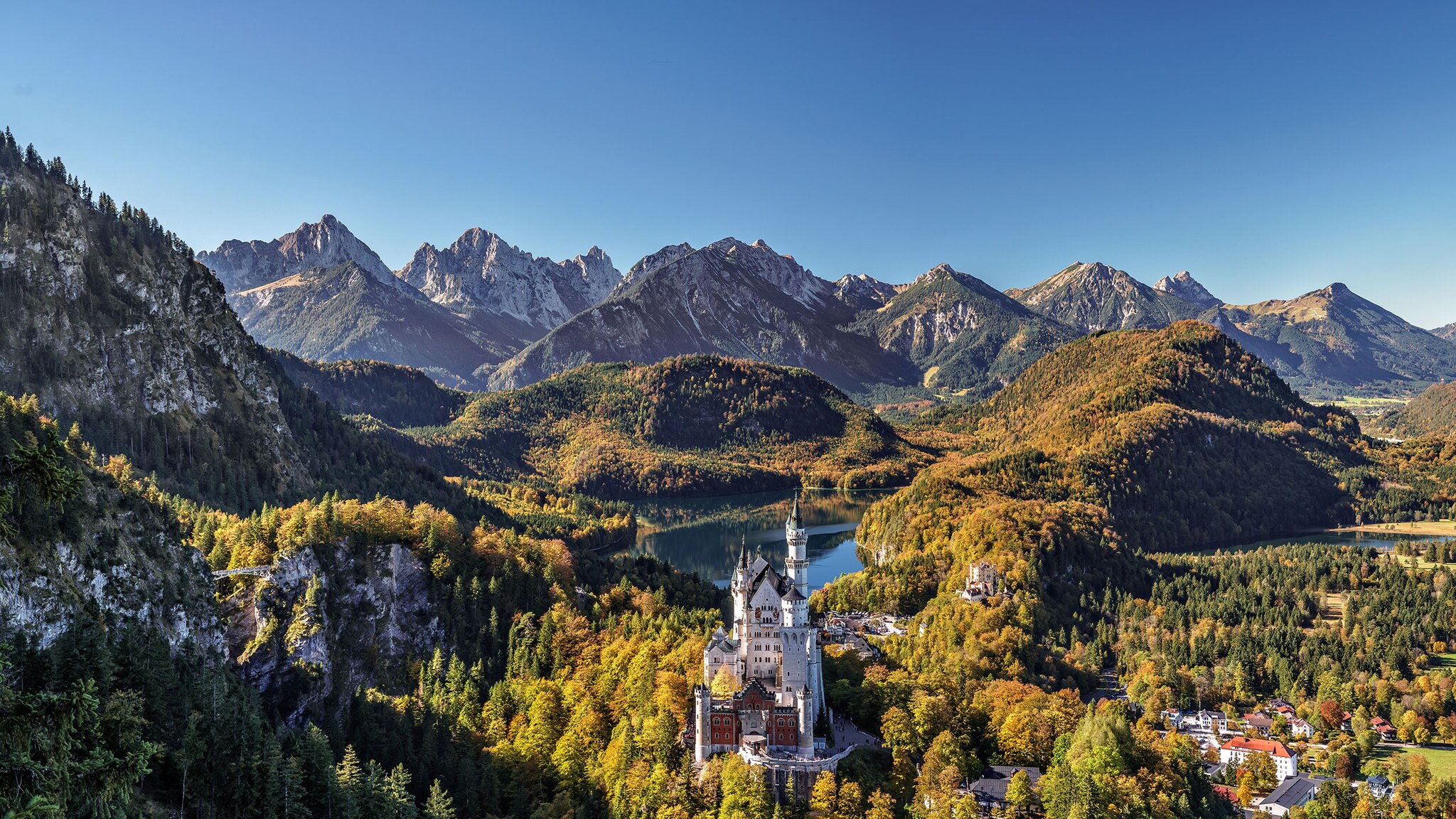 Umgeben von Bergen und Natur steht ein kleines Schloss.