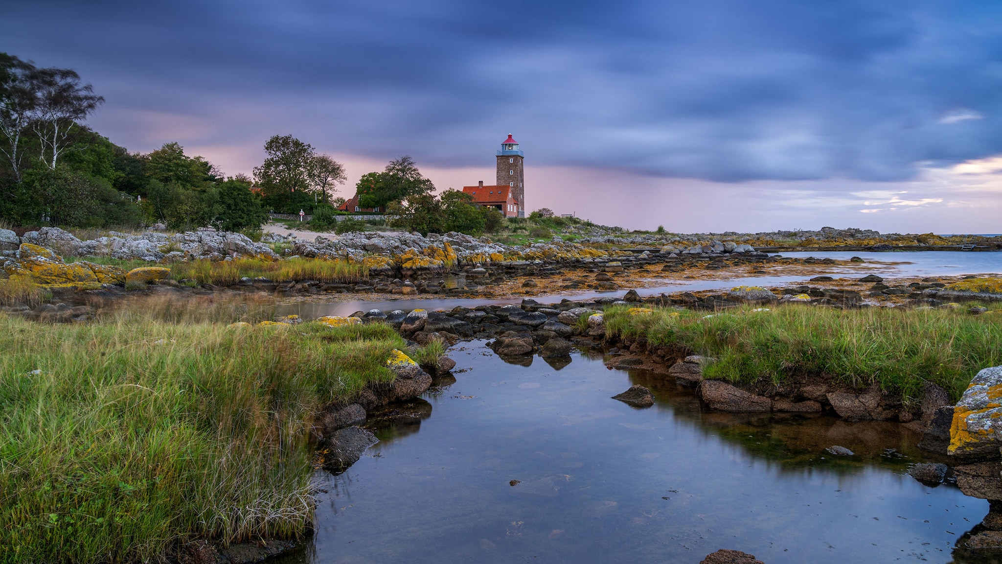 An einem Fjord liegt ein Haus umgeben von Natur.