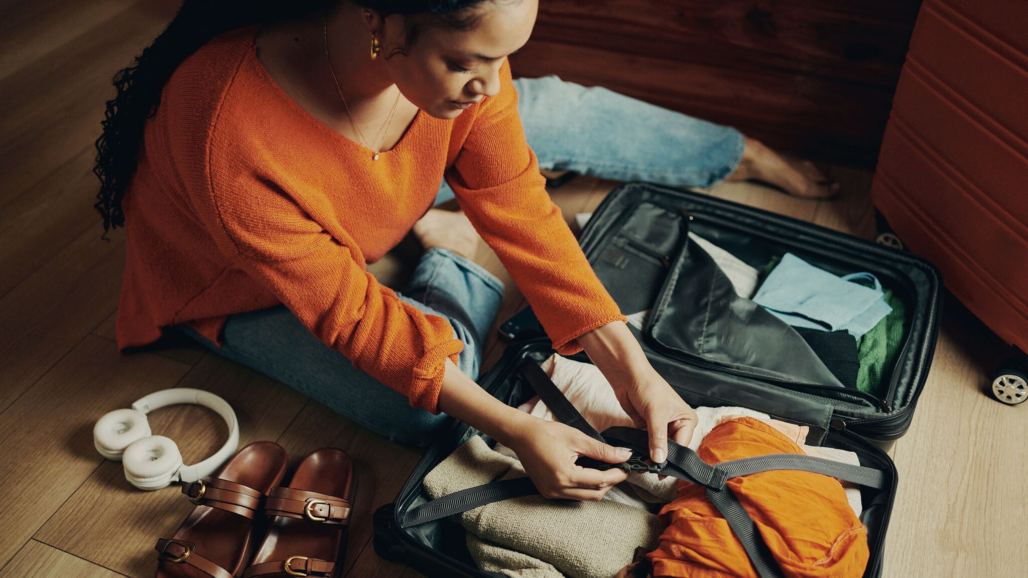 Eine Frau sitzt auf dem Boden und packt ihren Koffer.