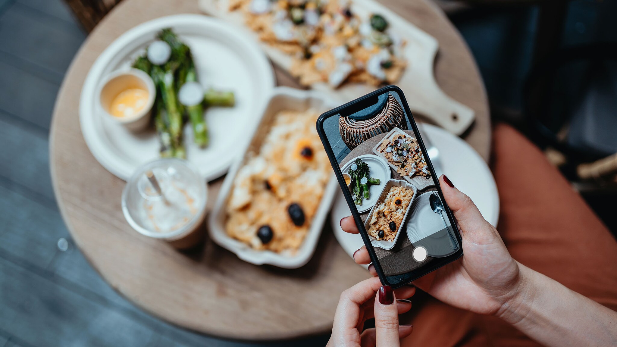 Eine Frau fotografiert mit dem Smartphone Essen.