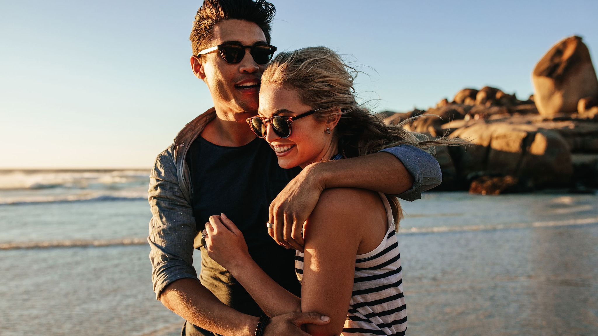 Ein spaziert Arm in Arm am Strand entlang.