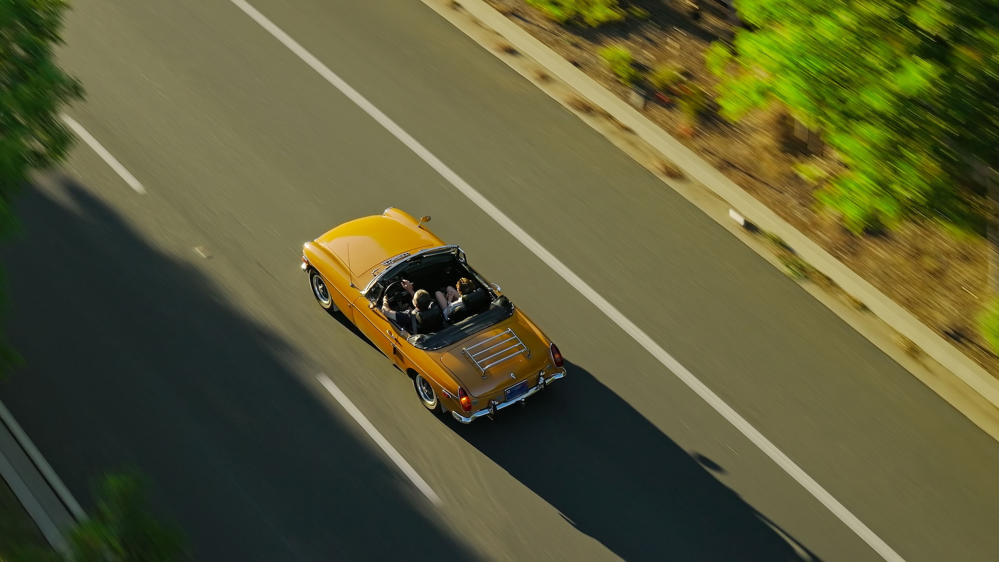 Ein gelber Oldtimer fährt auf der Straße.