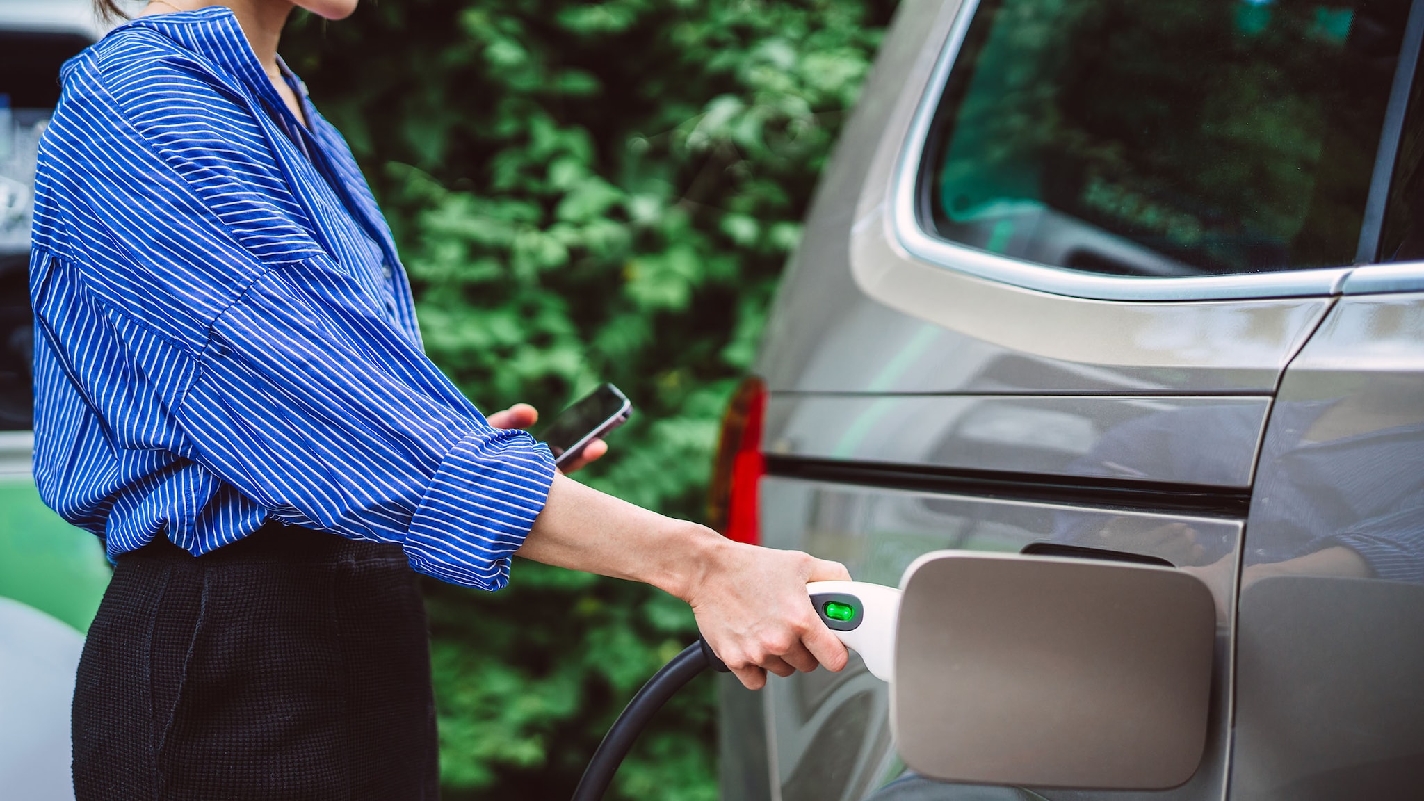 Eine Frau lädt ihr Elektroauto.