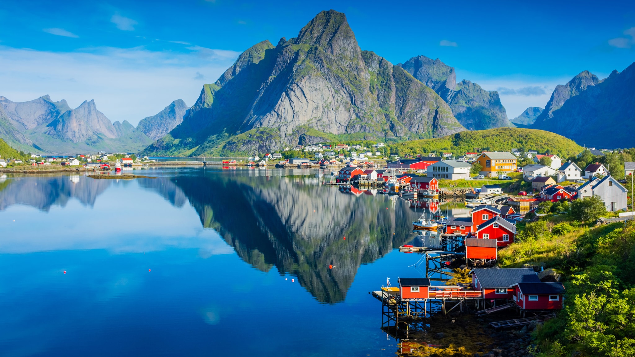 Typisch norwegische Siedlung mit roten Häusern an tiefblauem Wasser und Bergen im Hintergrund.