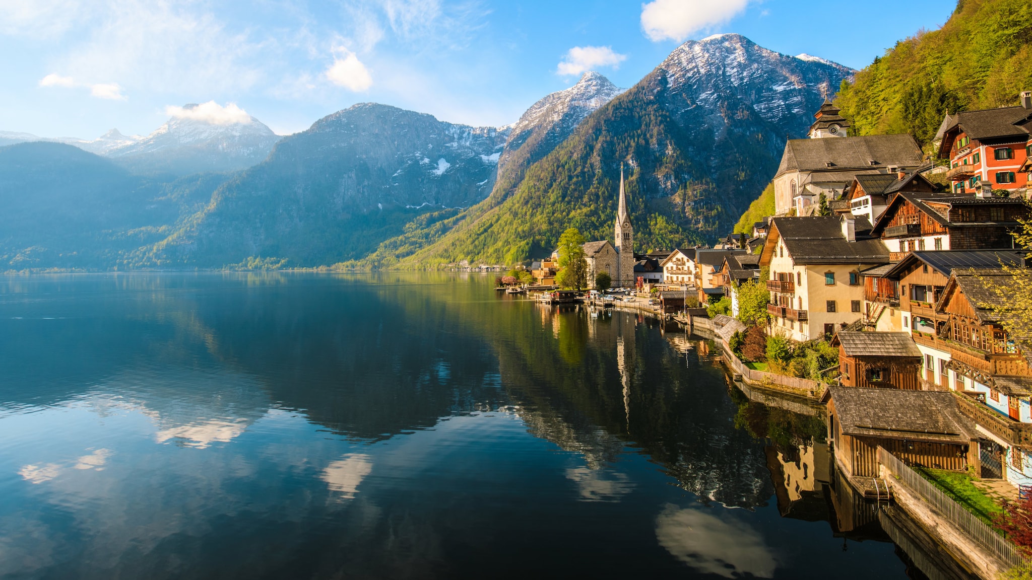 Idyllisches österreichisches Dorf mit klassischen Fachwerkhäusern, die sich in einem See spiegeln.