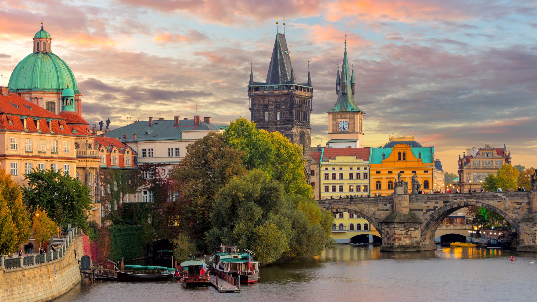 Blick auf berühmte Prager Wahrzeichen mit Türmen und Brücke bei Sonnenuntergang.