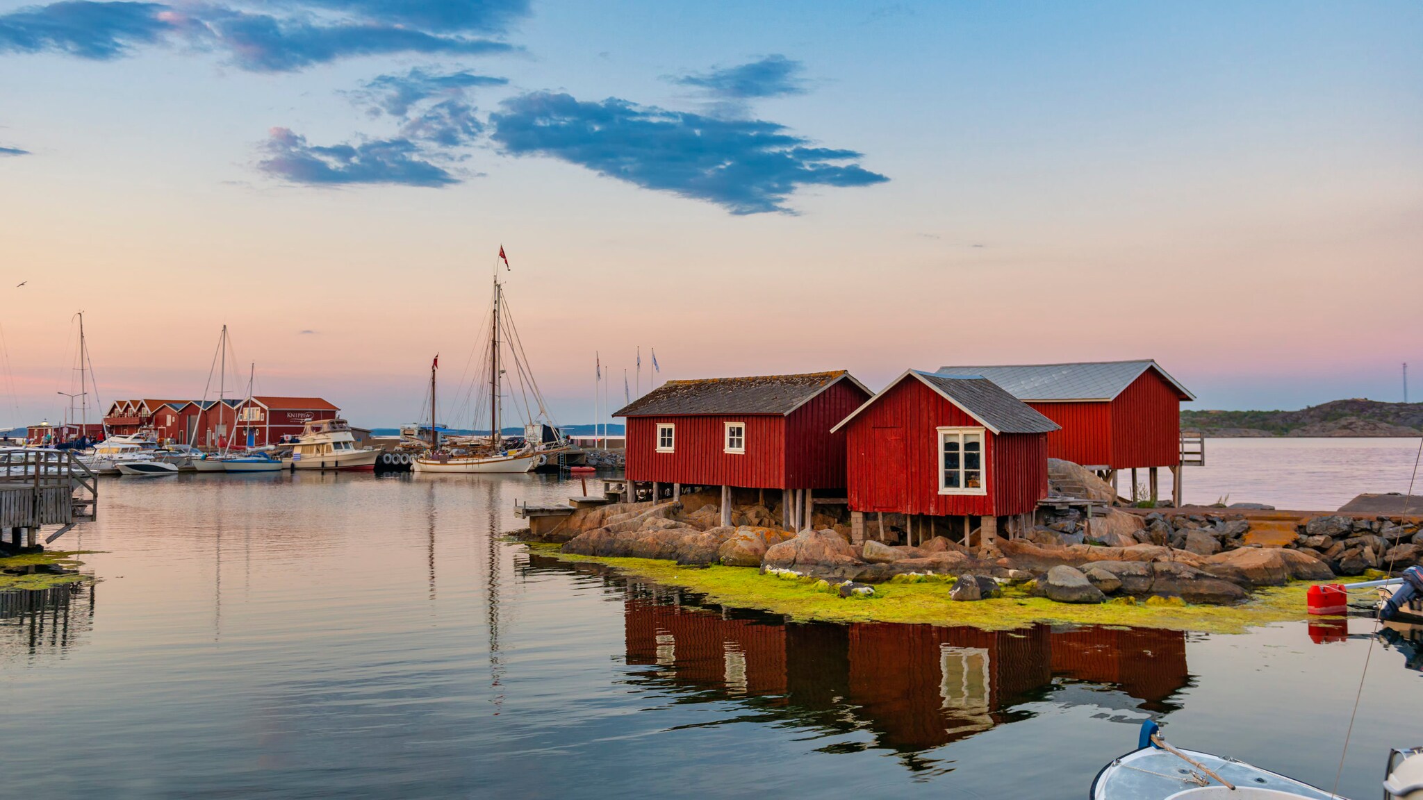Abendstimmung mit rote schwedische Holzhäuser direkt am Wasser.