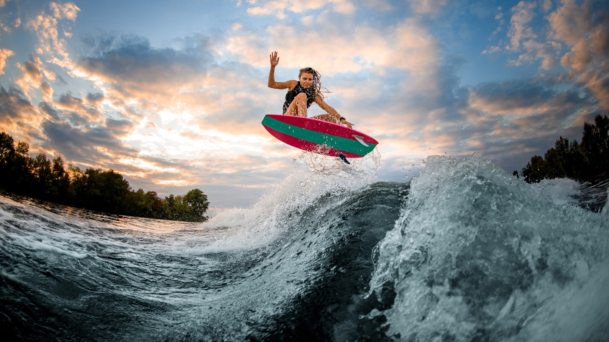 Surferin mit einem rot-grünen Bord gleitet über den Wellen.