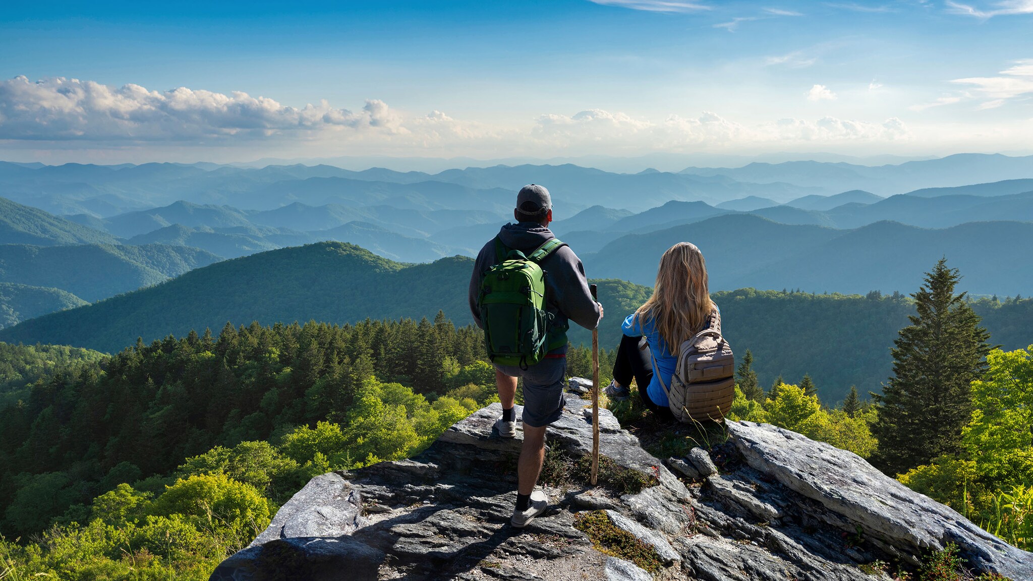 Ein Mann und eine Frau stehen auf einem Berg und schauen in die Ferne.