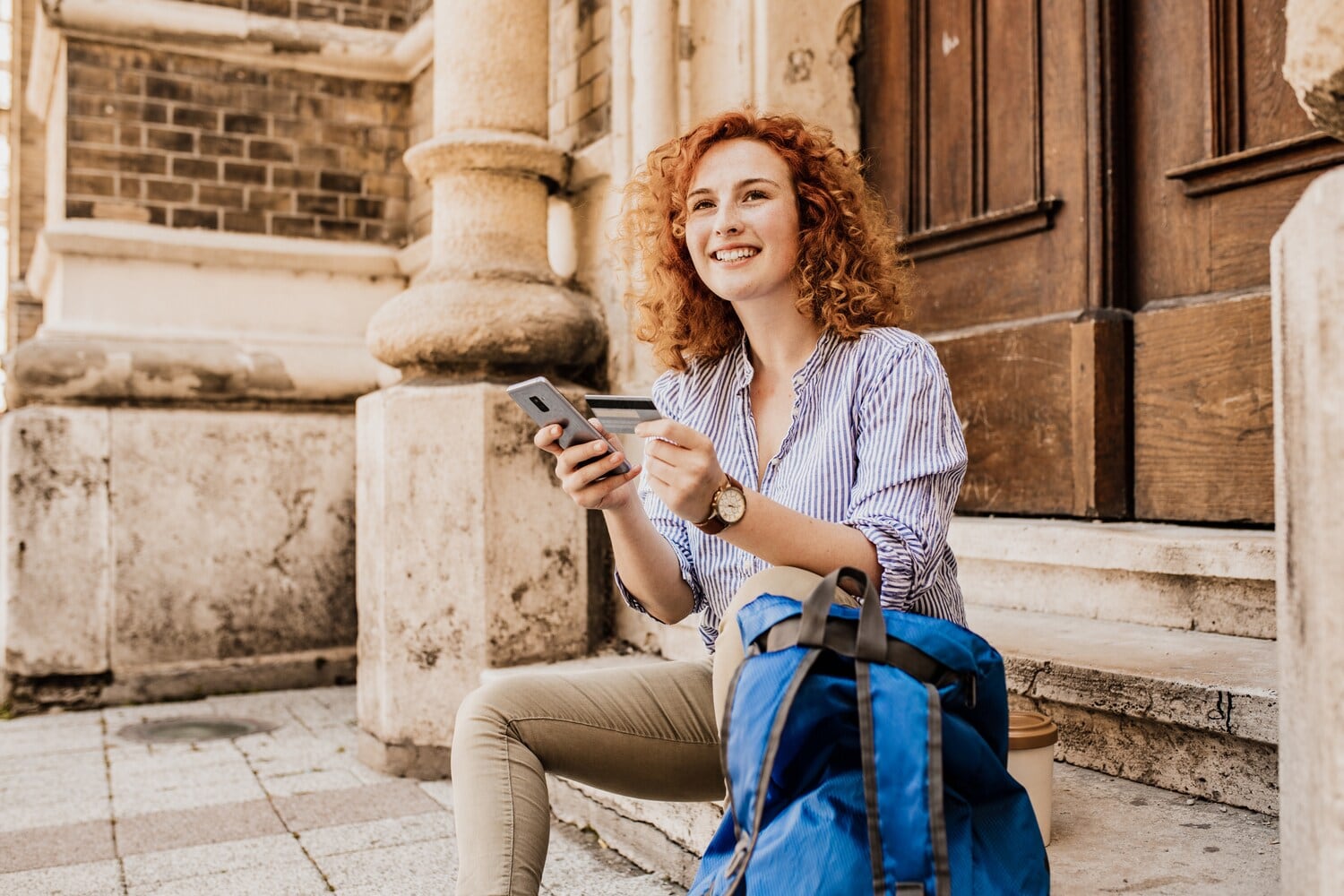 Junge Frau auf einer Treppe sitzend mit Kreditkarte und Smartphone in der Hand Junge Frau auf einer Treppe sitzend mit Kreditkarte und Smartphone in der Hand