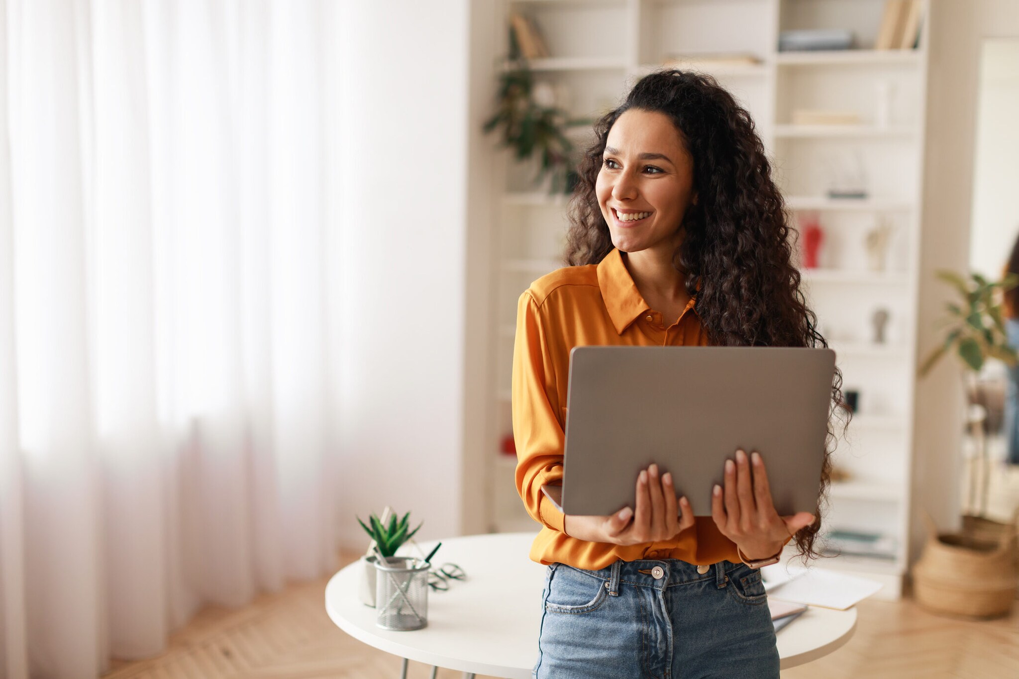 Eine Person lehnt an einem runden Tisch und hält ein geöffnetes Notebook in den Händen. Eine Person lehnt an einem runden Tisch und hält ein geöffnetes Notebook in den Händen.