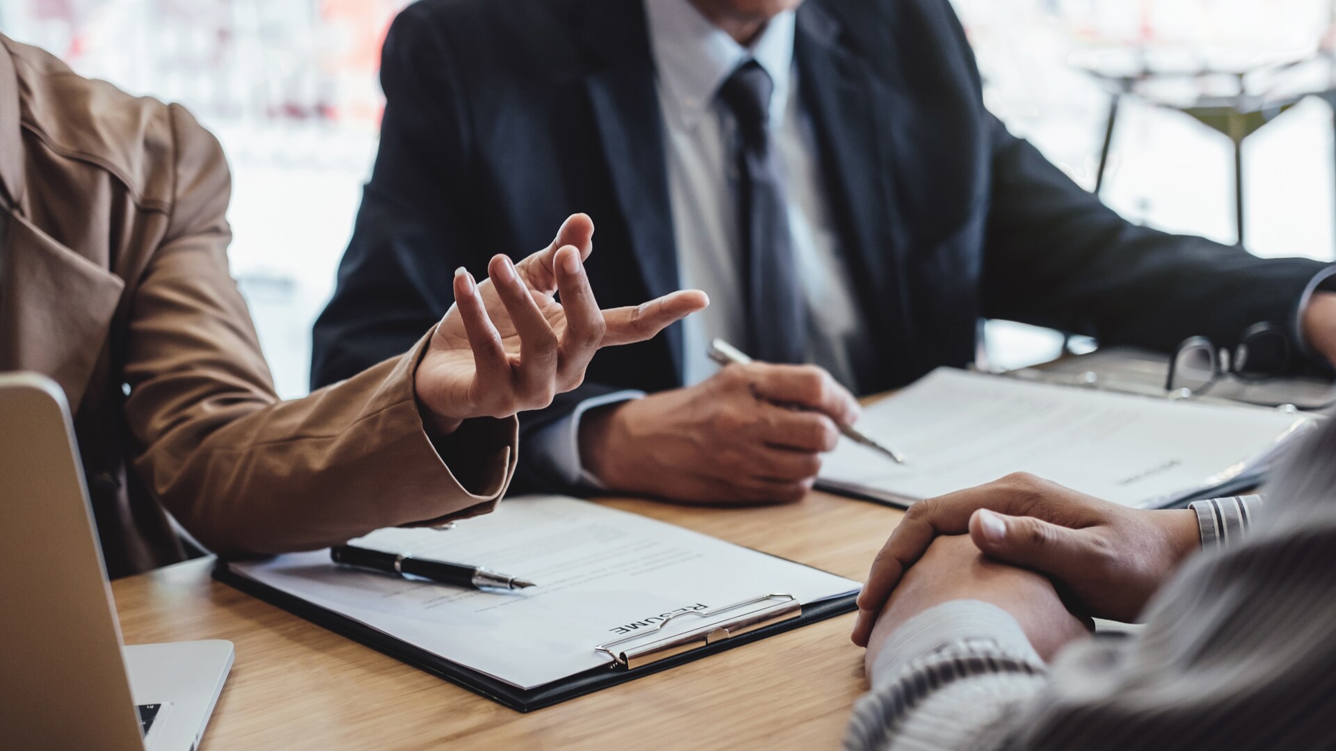 Nahaufnahme eines Verhandlungstisches an dem sich mehrere Personen unterhalten.