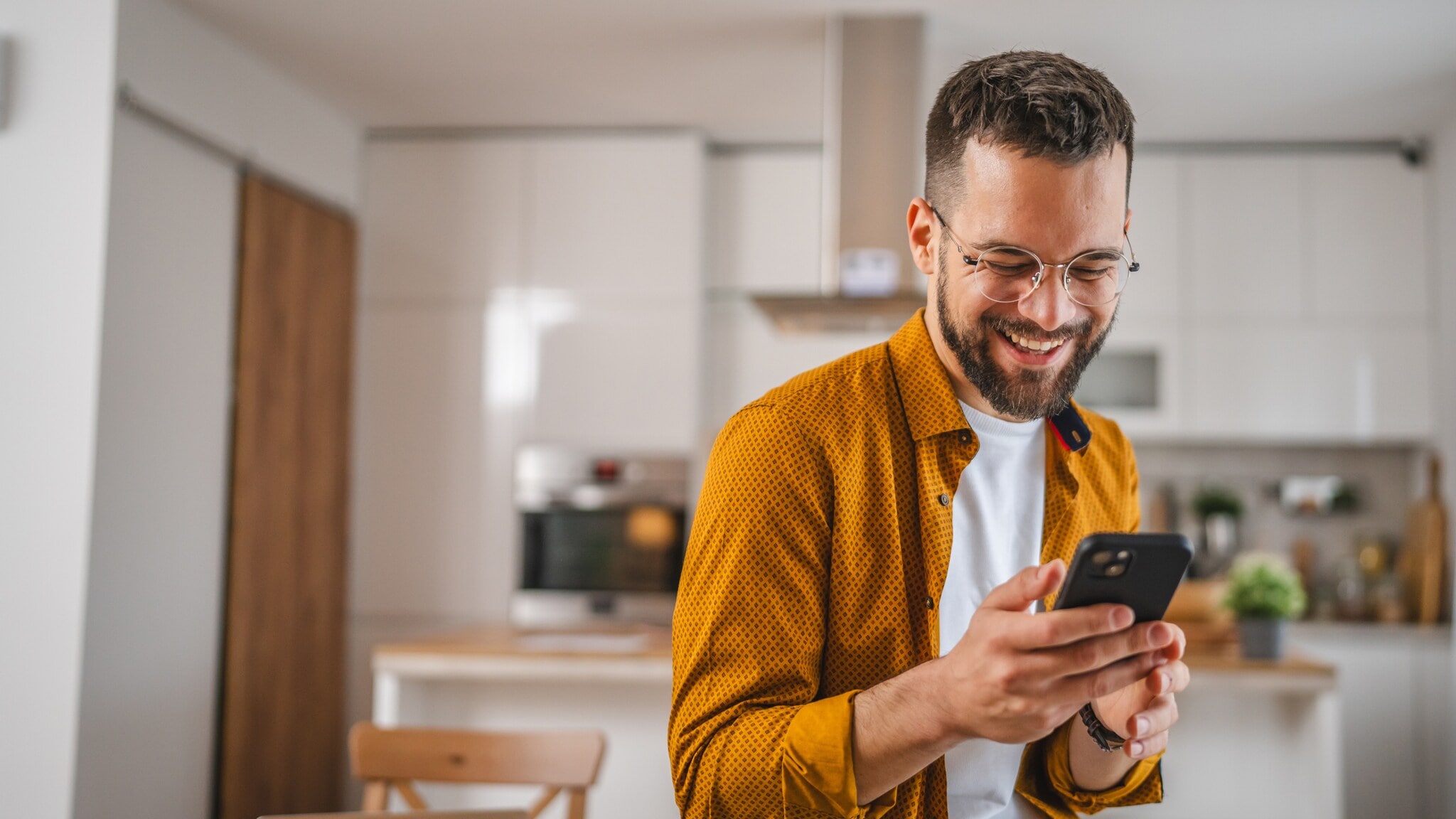 Eine Person hält ein Smartphone in den Händen und blickt lächelnd drauf. Eine Person hält ein Smartphone in den Händen und blickt lächelnd drauf.