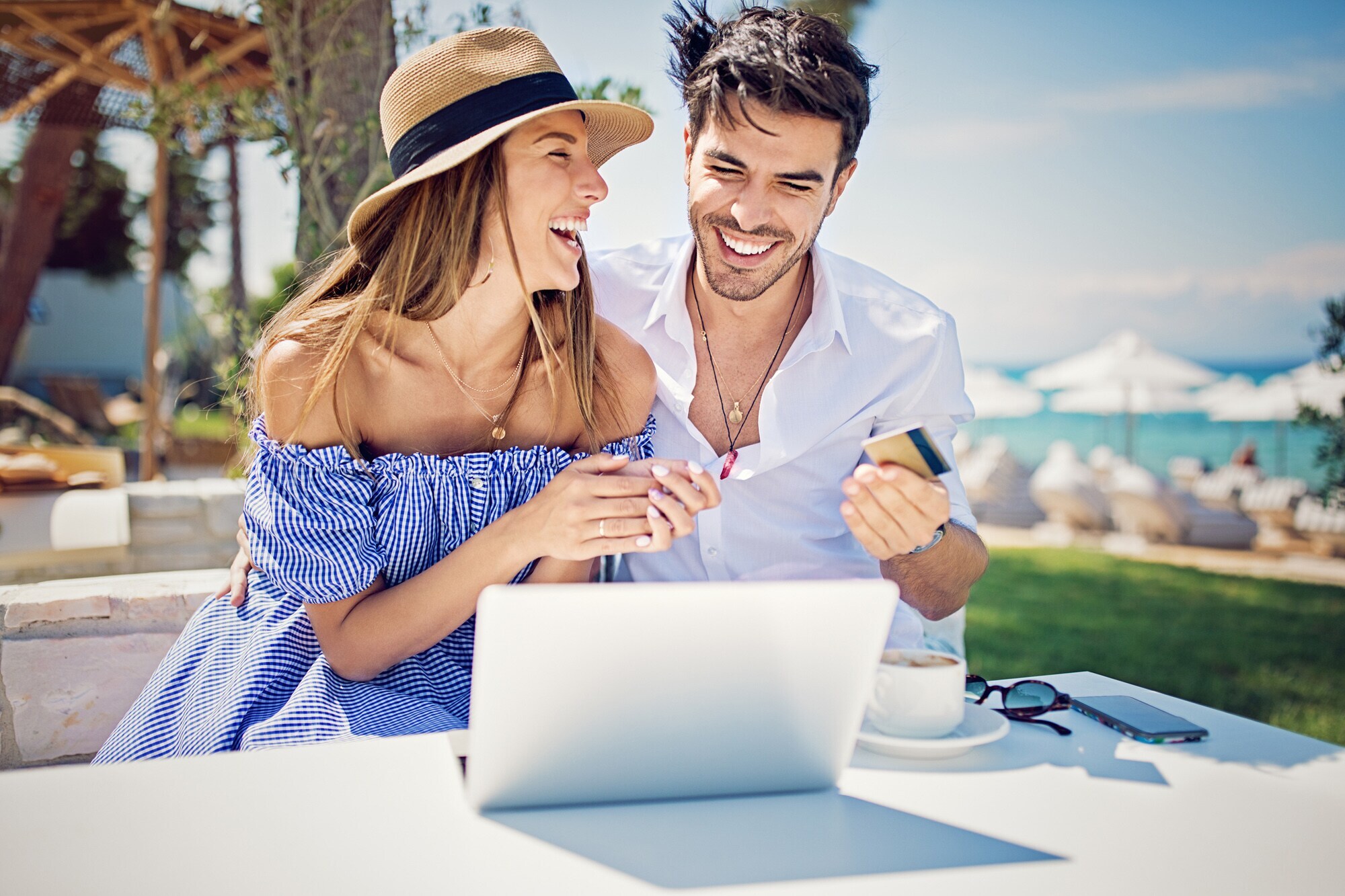 Ein fröhliches Pärchen sitzt im Urlaub am Laptop Ein fröhliches Pärchen sitzt im Urlaub am Laptop