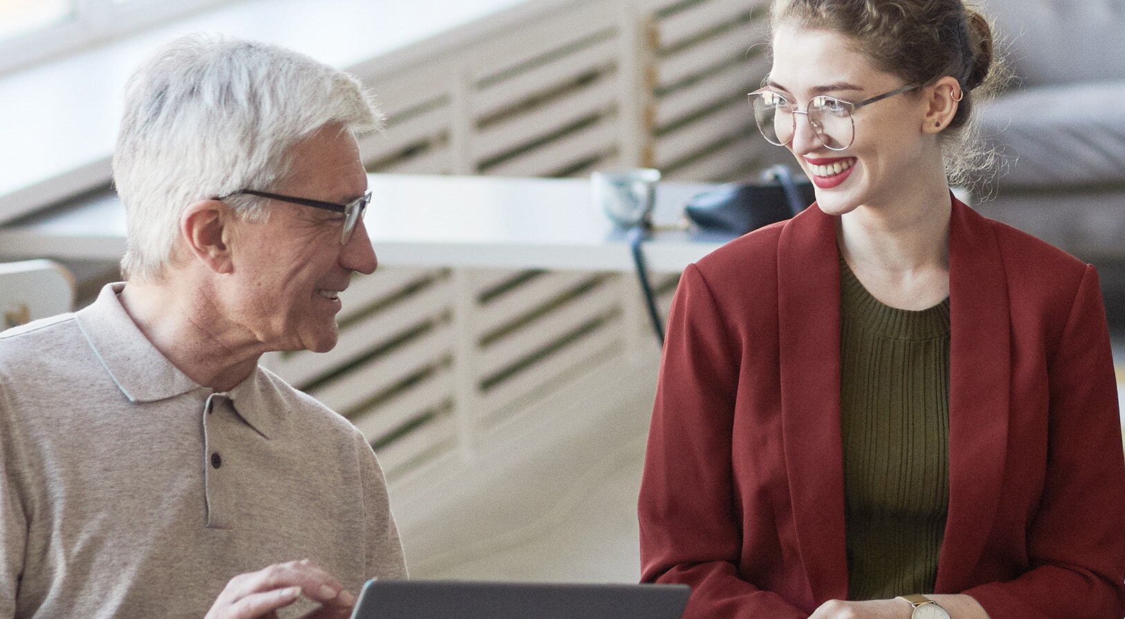 altersdiversitaet-in-unternehmen-p_ Jüngere und ältere Mitarbeitende eines Unternehmens halten gut gelaunt ein Meeting ab.