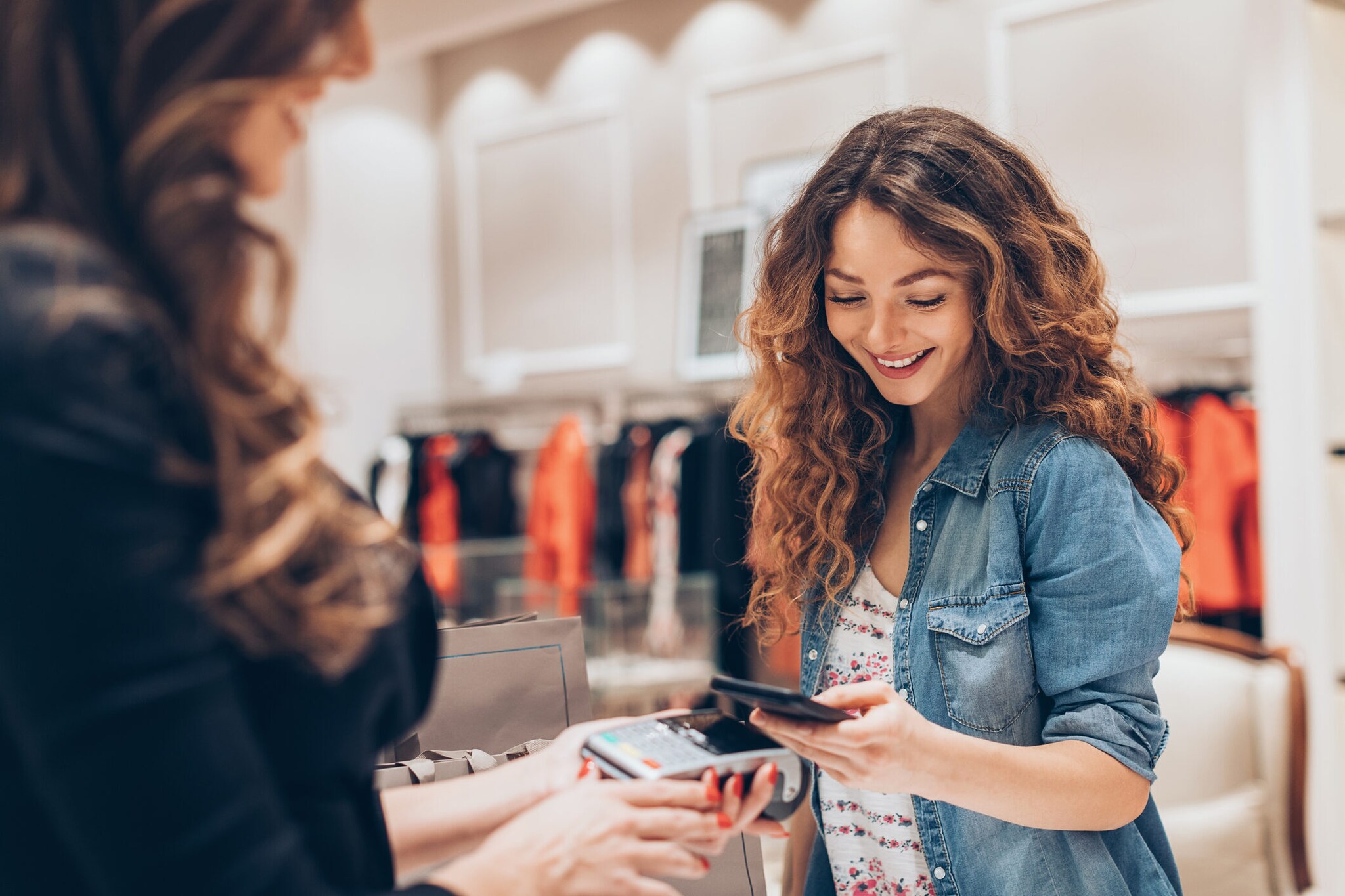 Eine Person bezahlt mit ihrem Smartphone in einem Bekleidungsgeschäft.