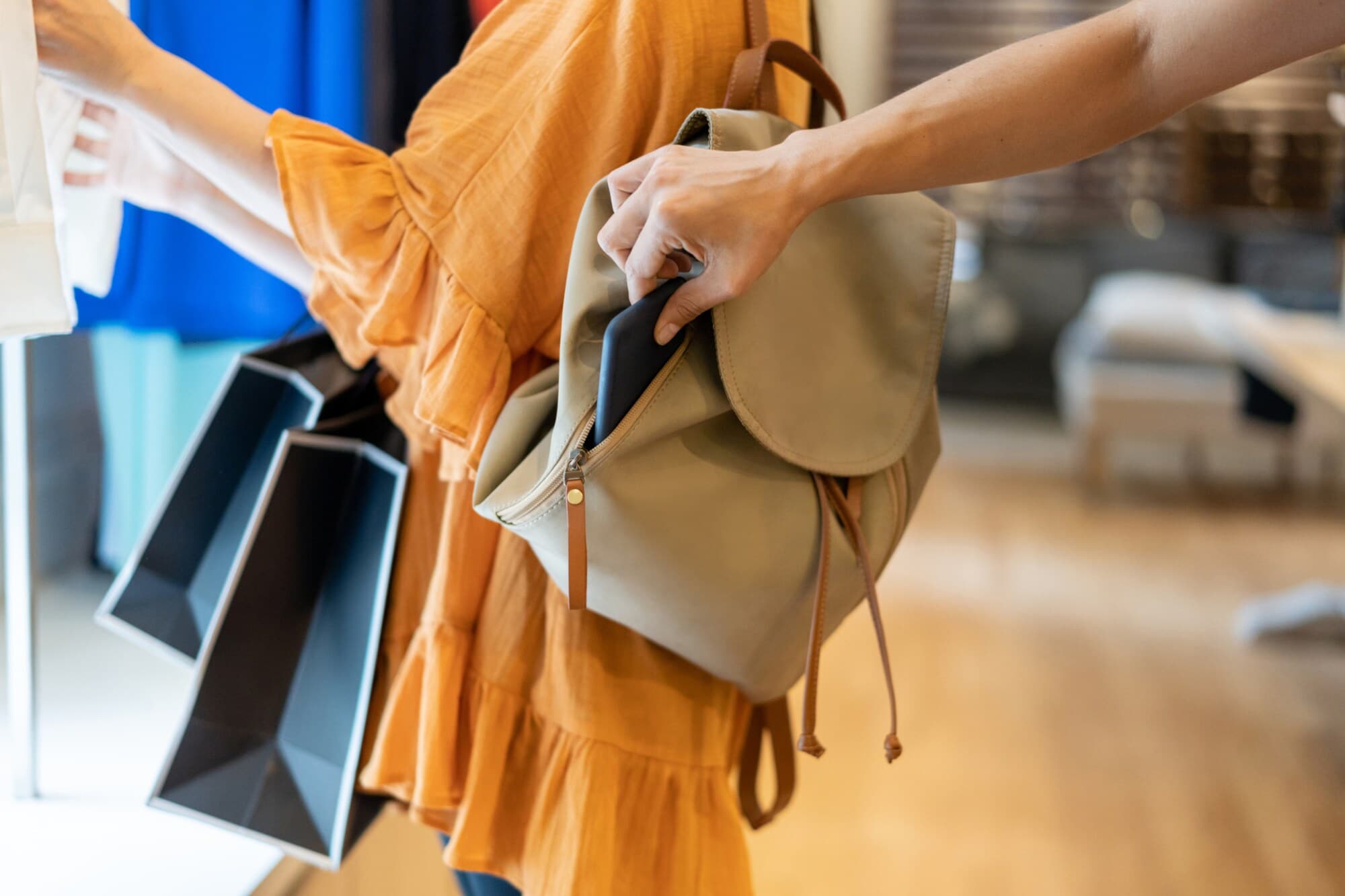 Nahaufnahme einer Hand, die ein Smartphone aus einem Rucksack entwendet. Nahaufnahme einer Hand, die ein Smartphone aus einem Rucksack entwendet.