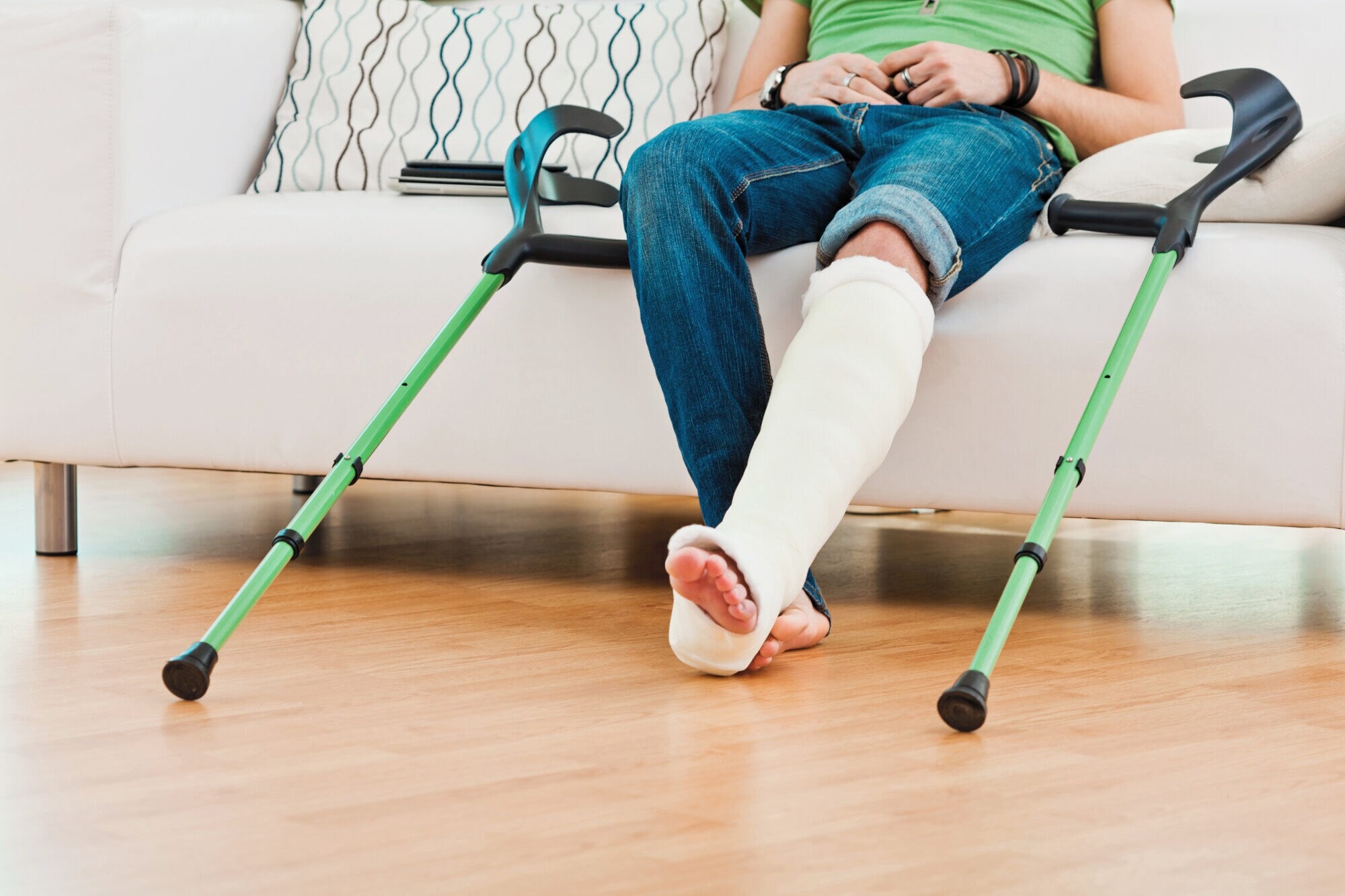 UV-knochenbruchaAufnahme der Beine einer Person, die auf einem Sofa sitzt und ein eingegipstes Bein hat. Aufnahme der Beine einer Person, die auf einem Sofa sitzt und ein eingegipstes Bein hat.