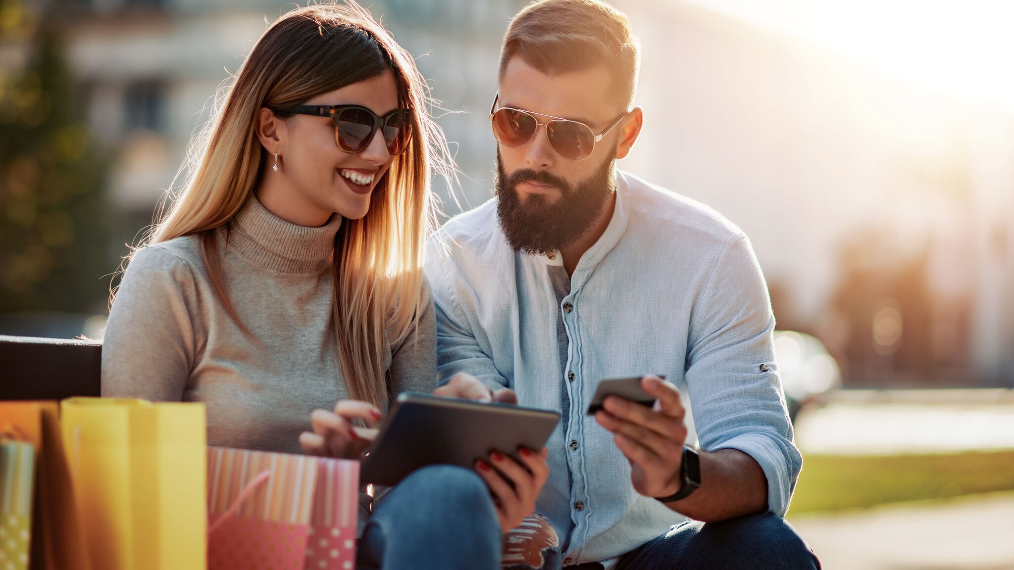 Eine Frau und ein Mann sitzen in einer Stadt, er hält eine Kreditkarte in der Hand.