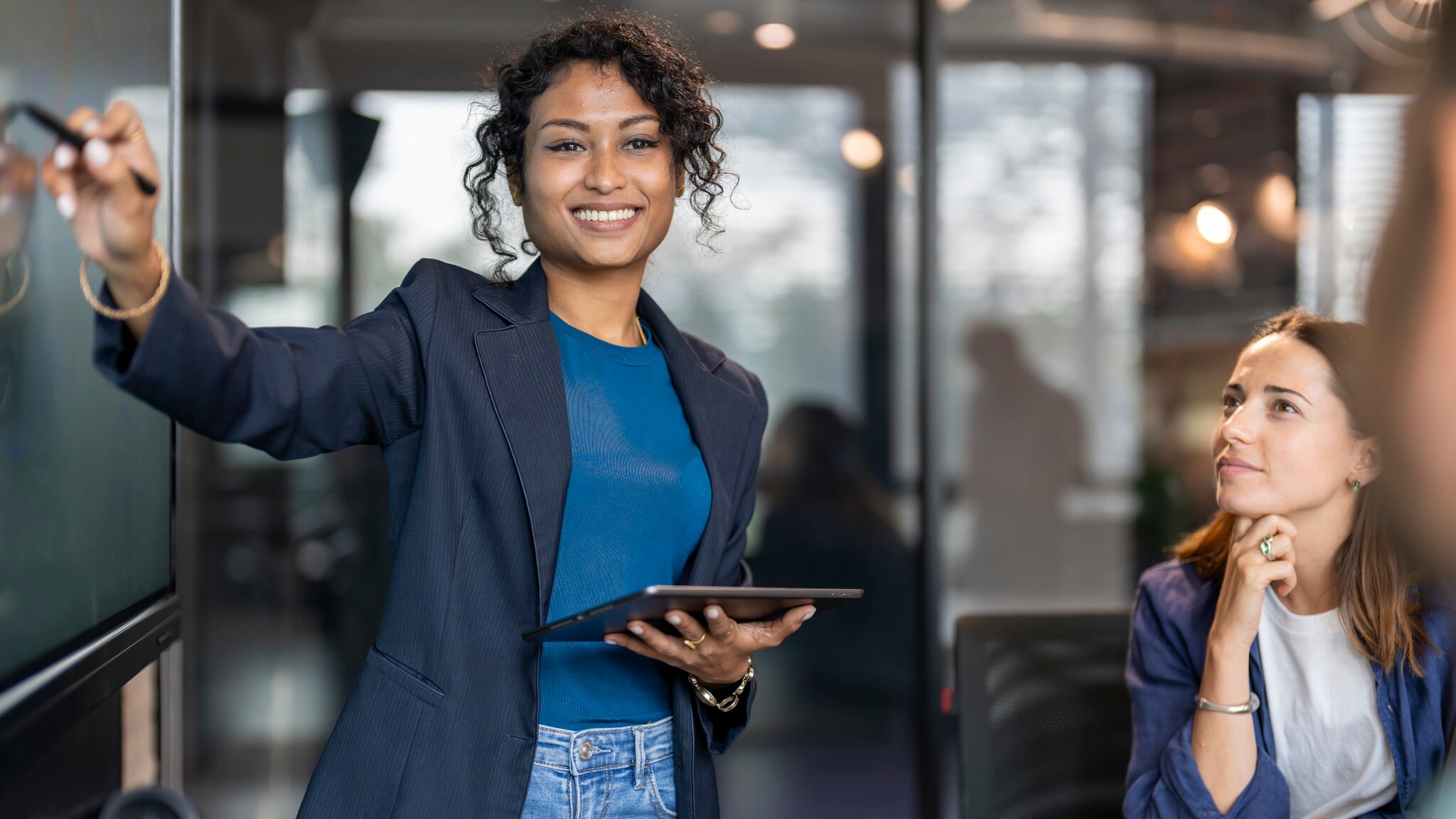 Porträt einer Geschäftsfrau mit Tablet in der Hand, die in einem Besprechungsraum eine Präsentation hält.