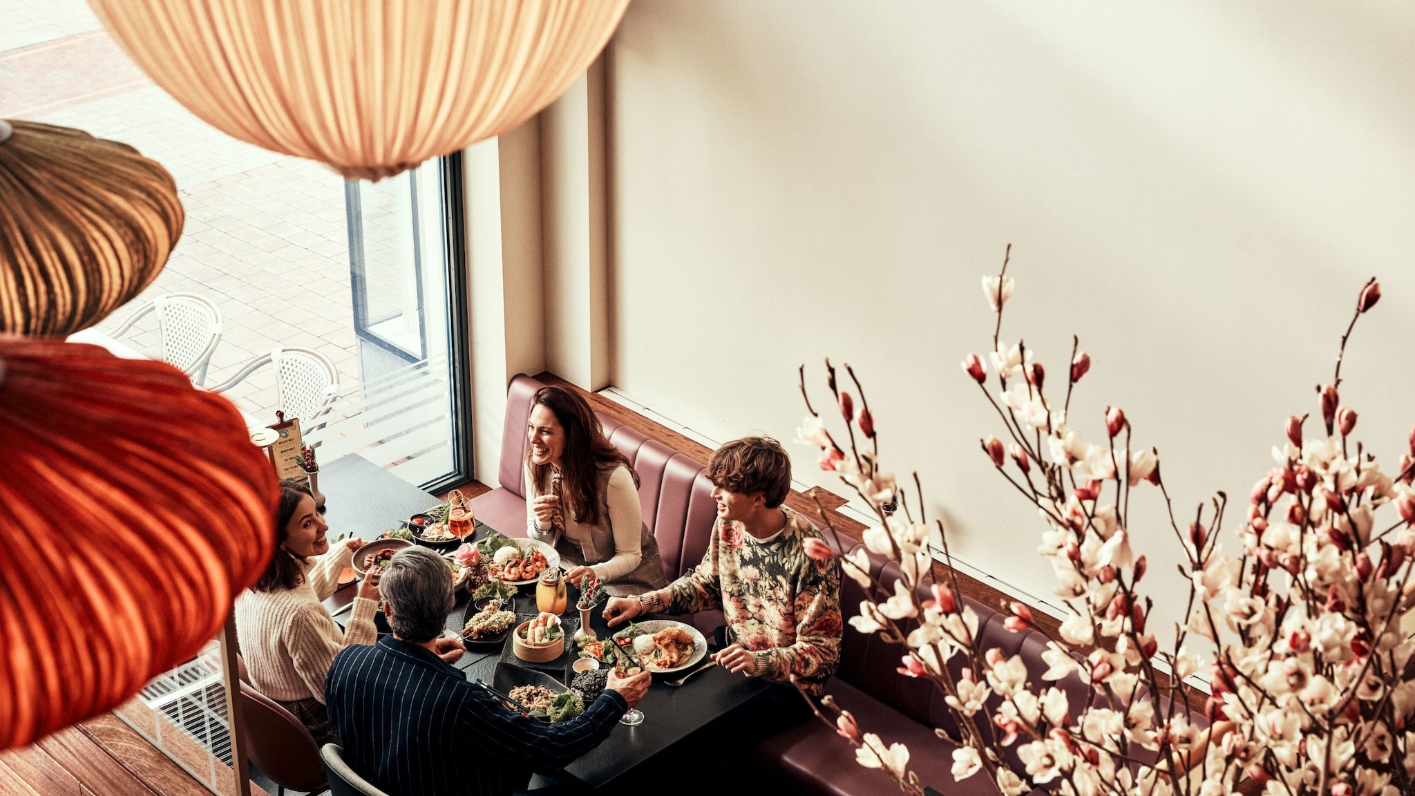 Vier Menschen sitzen in einem stilvoll-gemütlichen Restaurant an einem reichlich gedeckten Tisch. Vier Menschen sitzen in einem stilvoll-gemütlichen Restaurant an einem reichlich gedeckten Tisch.