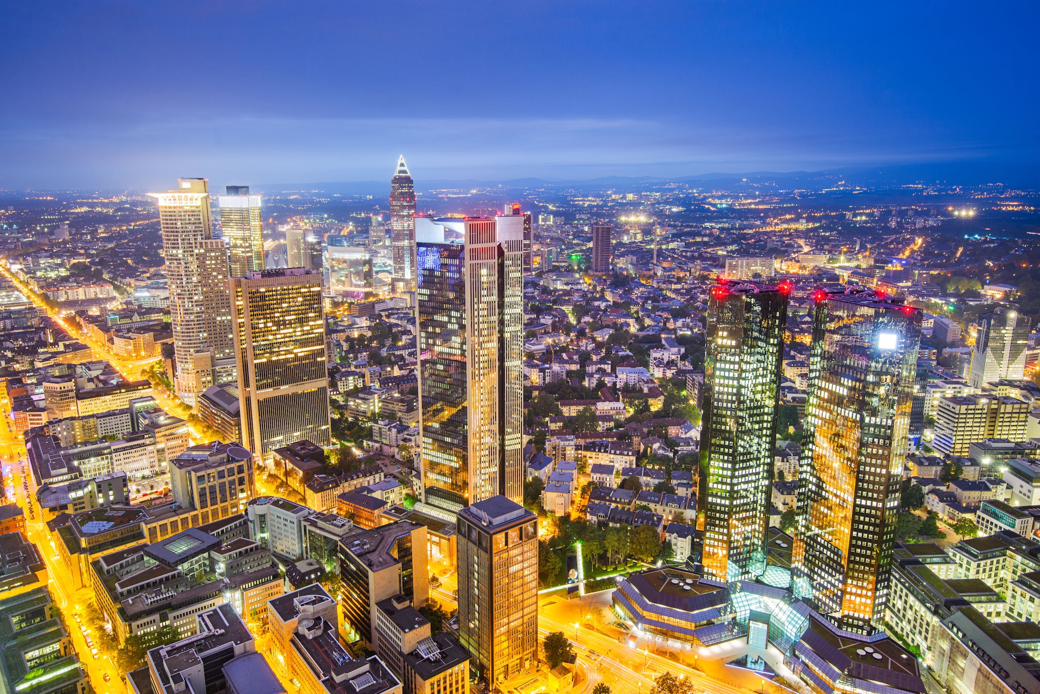 amex-magazin-frankfurt-fussball-skyline Blick von oben auf die beleuchteten Hochhäuser Frankfurts in der Dämmerung.