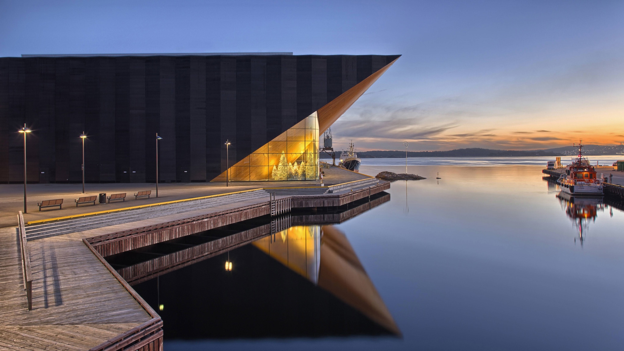 amex-magazin-kristiansand-norwegen-konzerthaus Direkt an einem Fjord steht ein modernes Gebäude mit einer großen Fensterfront.