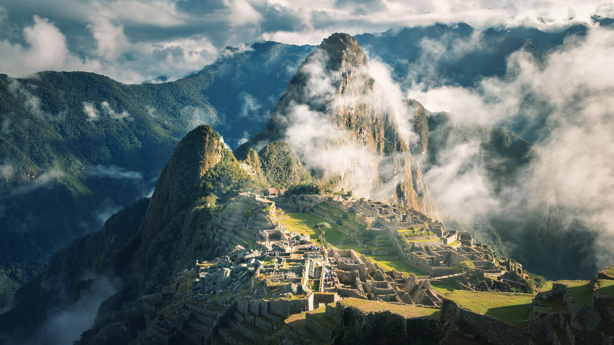 Auf einem sehr hohen Berg mitten in den Wolken stehen Ruinen.