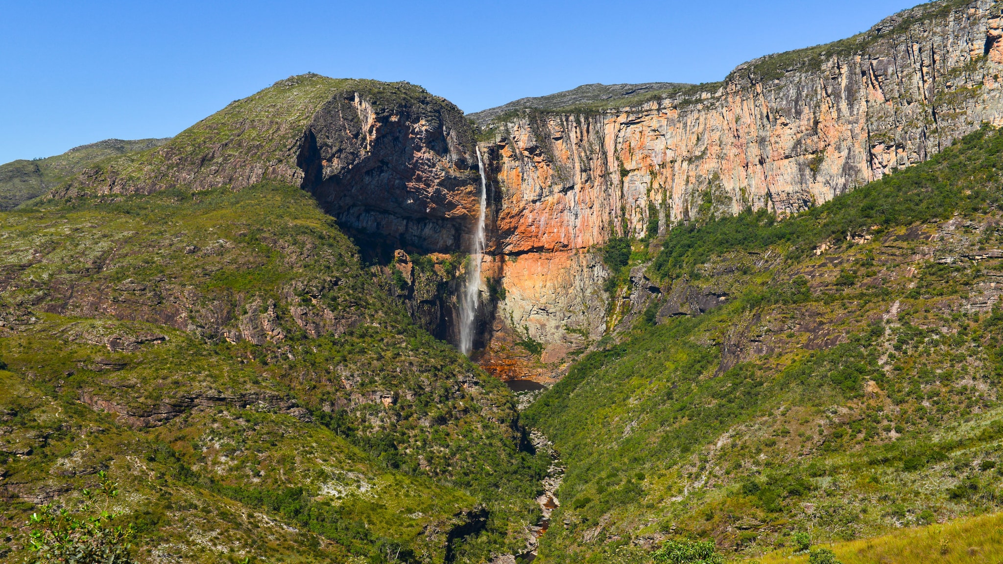 amex-magazin-wasserfaelle-brasilien-bergigen-landschaft Mitten in einer bergigen Landschaft fließt ein Wasserfall von einem Berg.