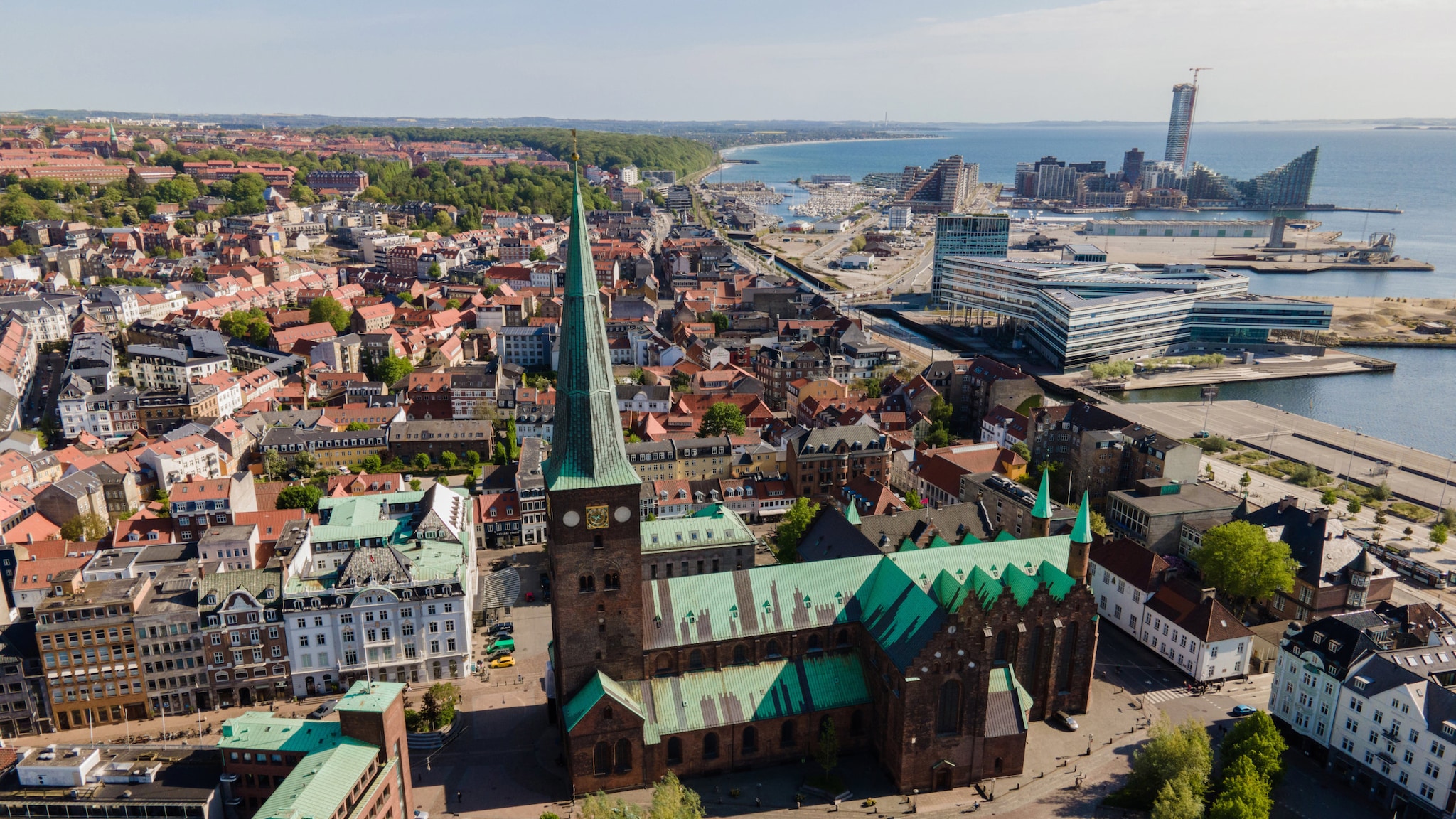 amex-magazin-aarhus-daenemark-kirche Vogelperspektive auf eine Stadt mit historischer Kirche und modernen Gebäuden.