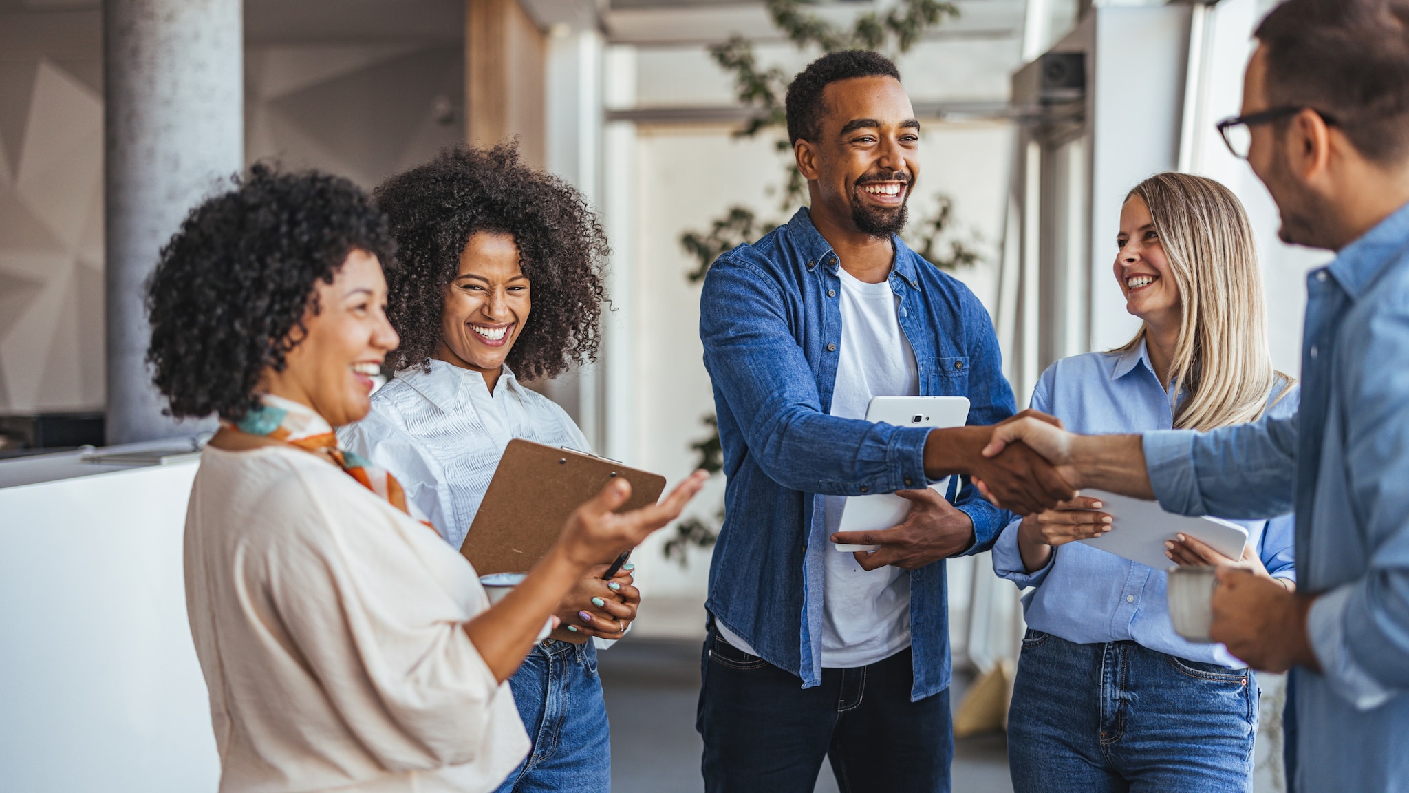 ersonen stehen zusammen, schütteln Hände und lächeln. 