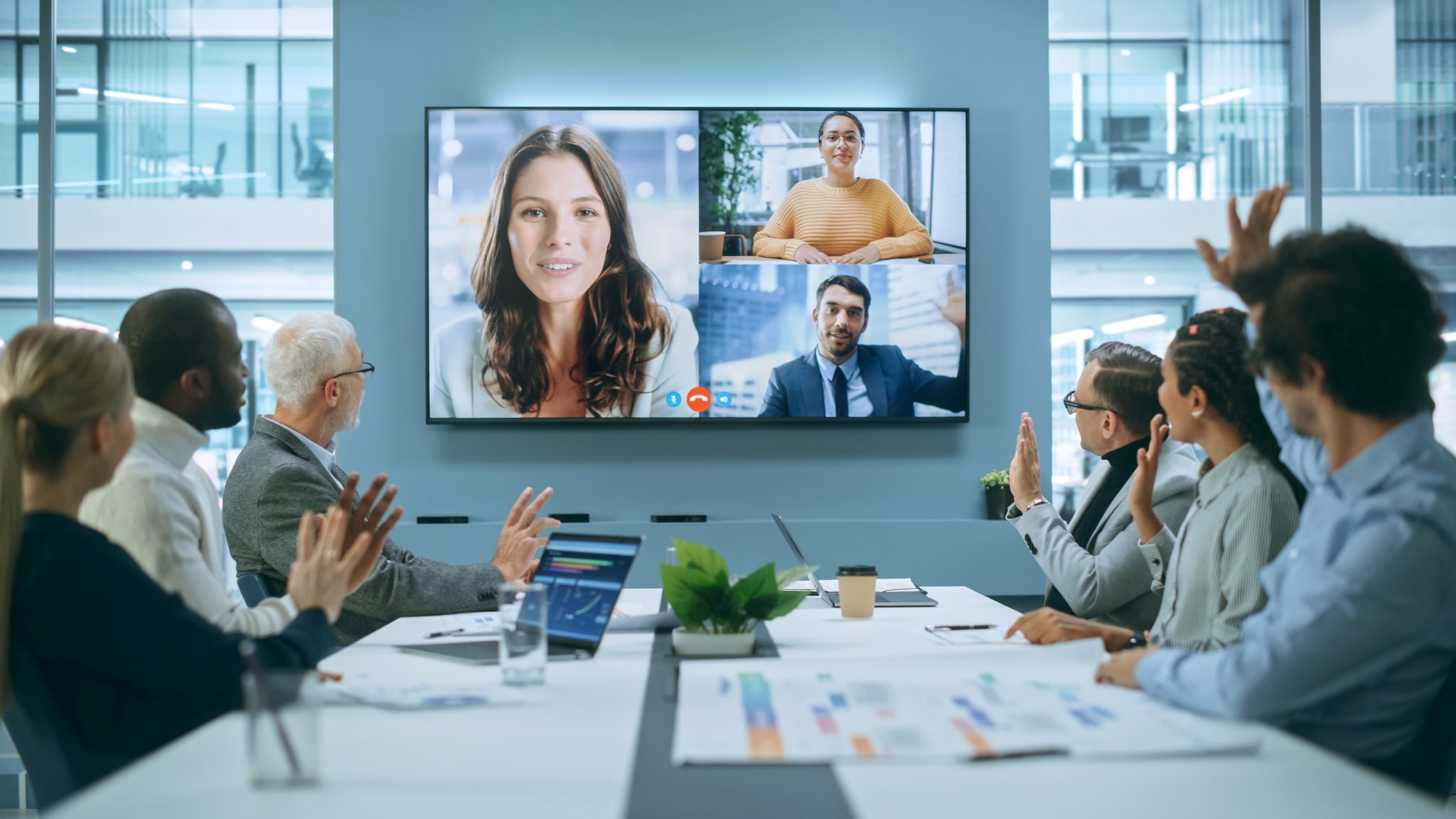 amex-sbs-event-networking-tools-meeting-monitor Während eines Meetings sind auf einem Monitor Personen zu sehen, die virtuell an einem Termin teilnehmen.